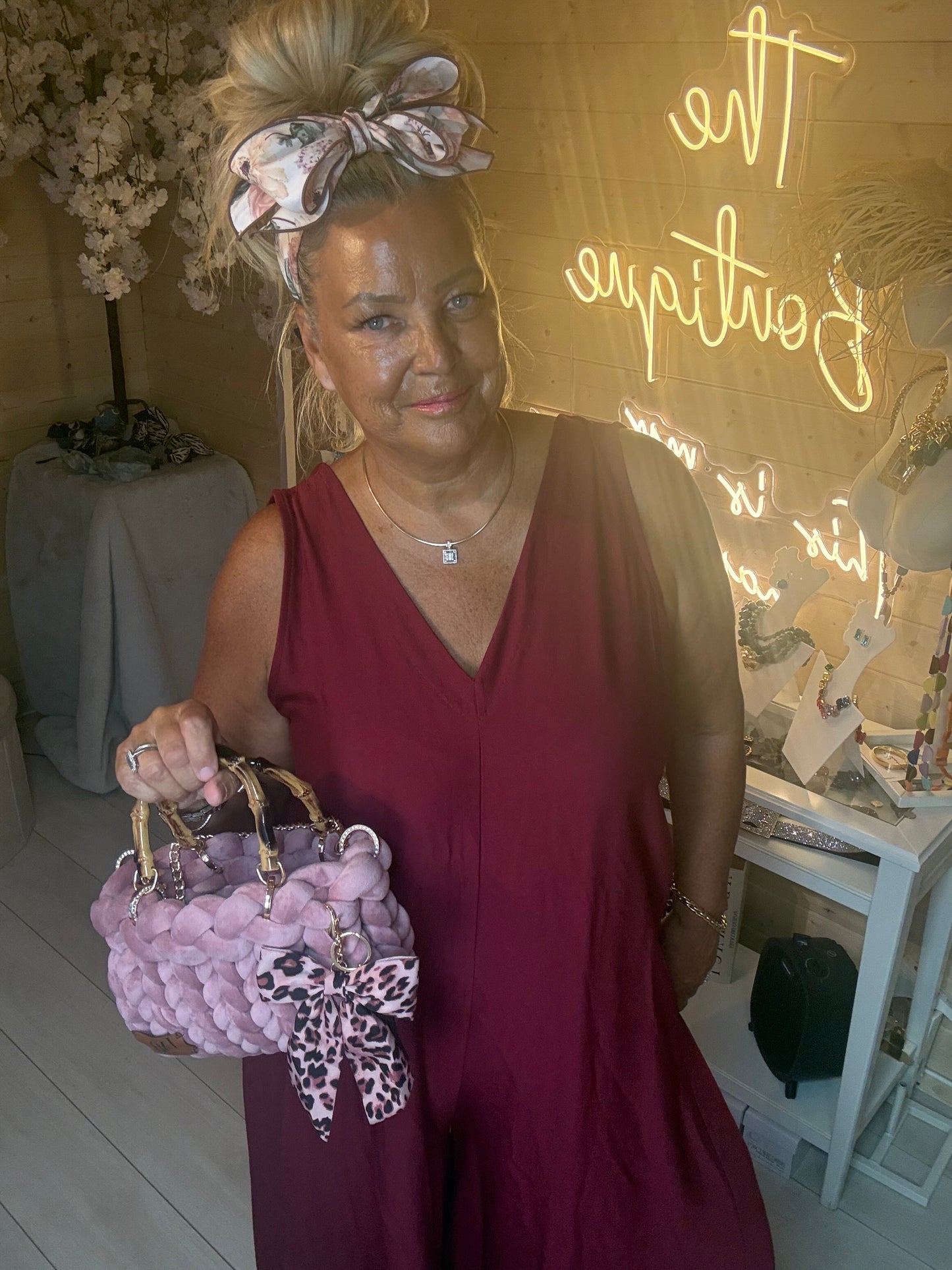 Close up of model holding Lavinia Chunky Woven Tote Bag in lilac with leopard print bow charm styled with Merlot Burgundy Jumpsuit