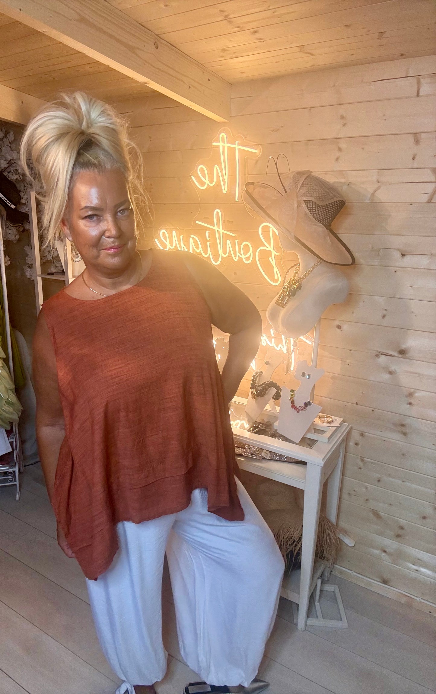 Rust fine knit top – close up three quarter view showing round neckline, short sleeve and layered double hem detail in rich terracotta colour