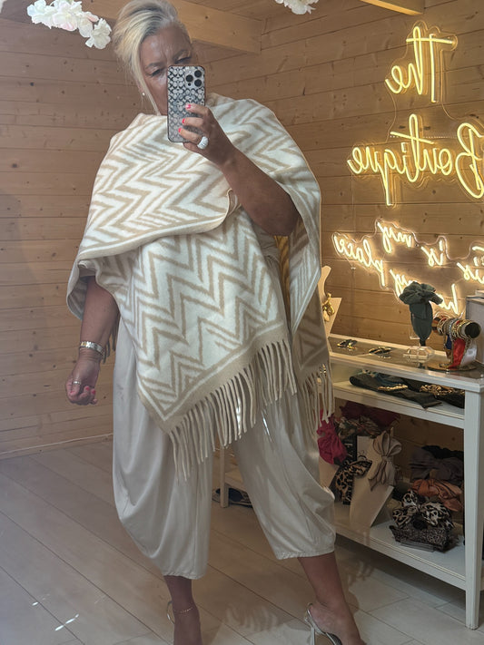 Front view of cream and white chevron patterned wrap cape showing pointed fringe hem