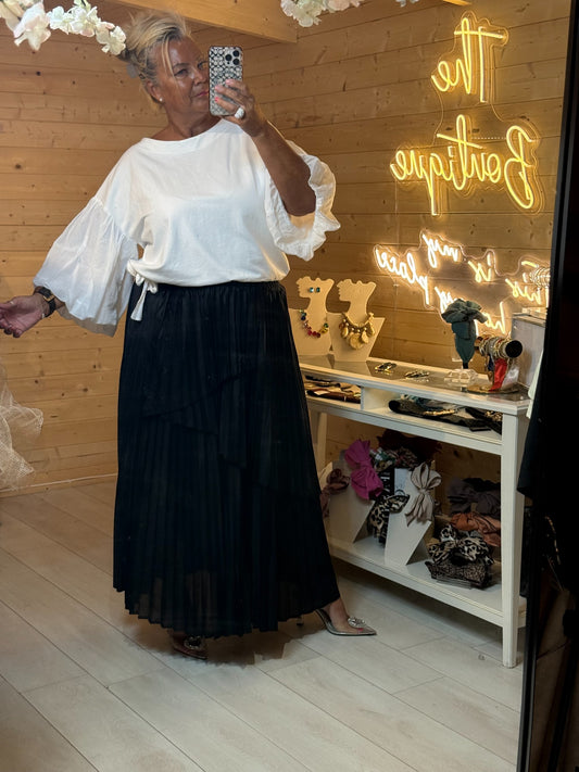 Long black pleated tiered skirt with flowing hem and elasticated waistband styled with white top
