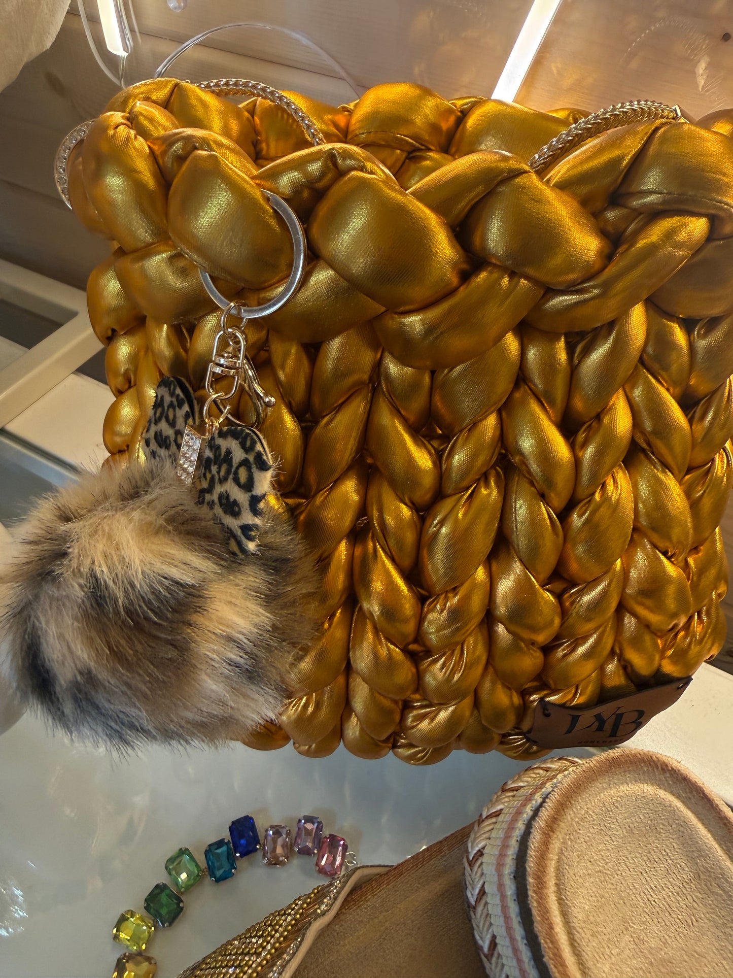 Gold rush metallic chunky braid bucket bag close up showing leopard print charm and faux fur pom pom