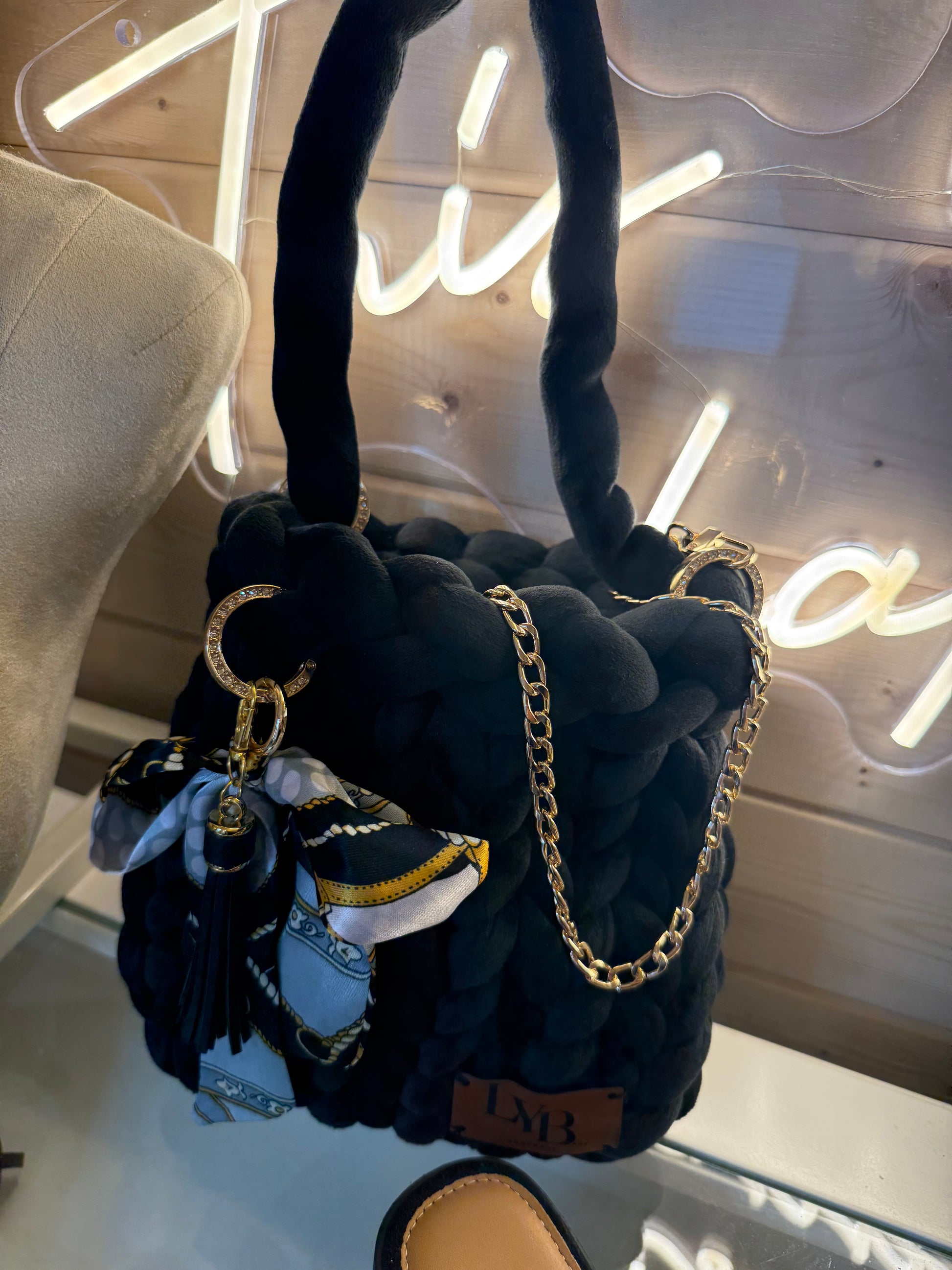 Midnight noir velvet chunky braid bucket bag held by top handle showing gold chain strap draping