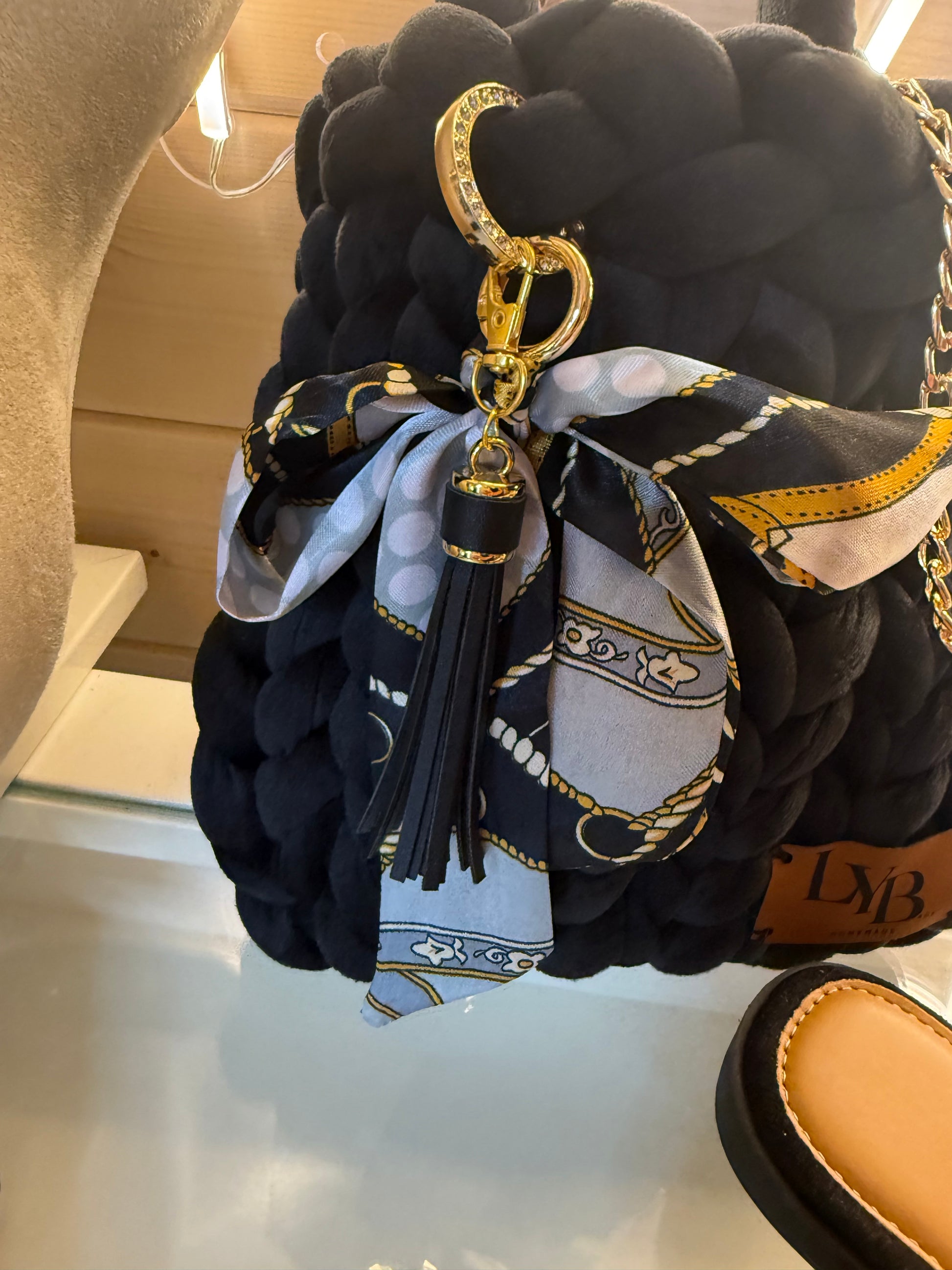 Midnight noir velvet chunky braid bucket bag close up of equestrian print silk scarf and black leather tassel charm
