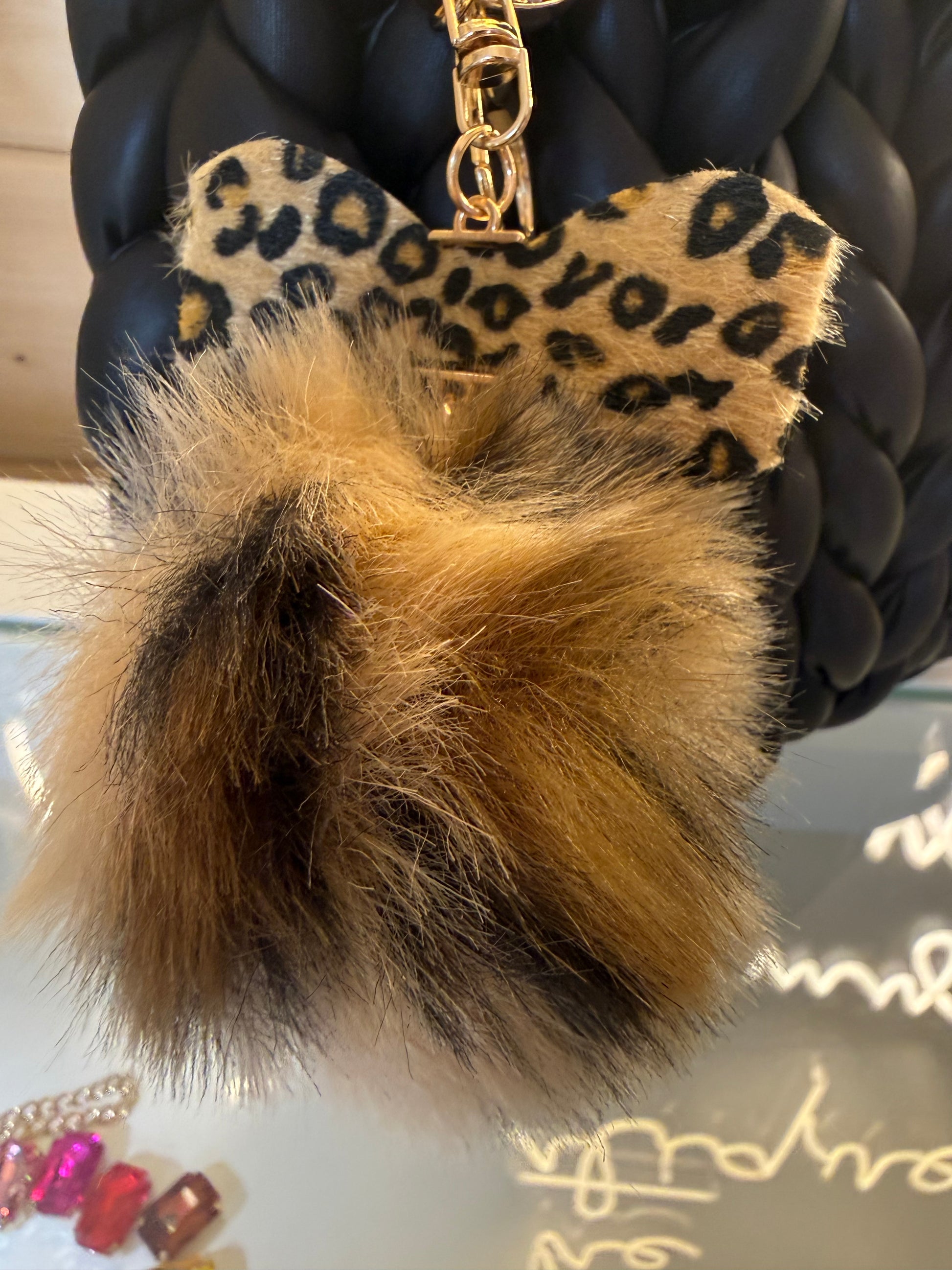 Wild at heart chunky braid faux leather bucket bag close up of leopard print heart charm and fluffy brown faux fur pom pom