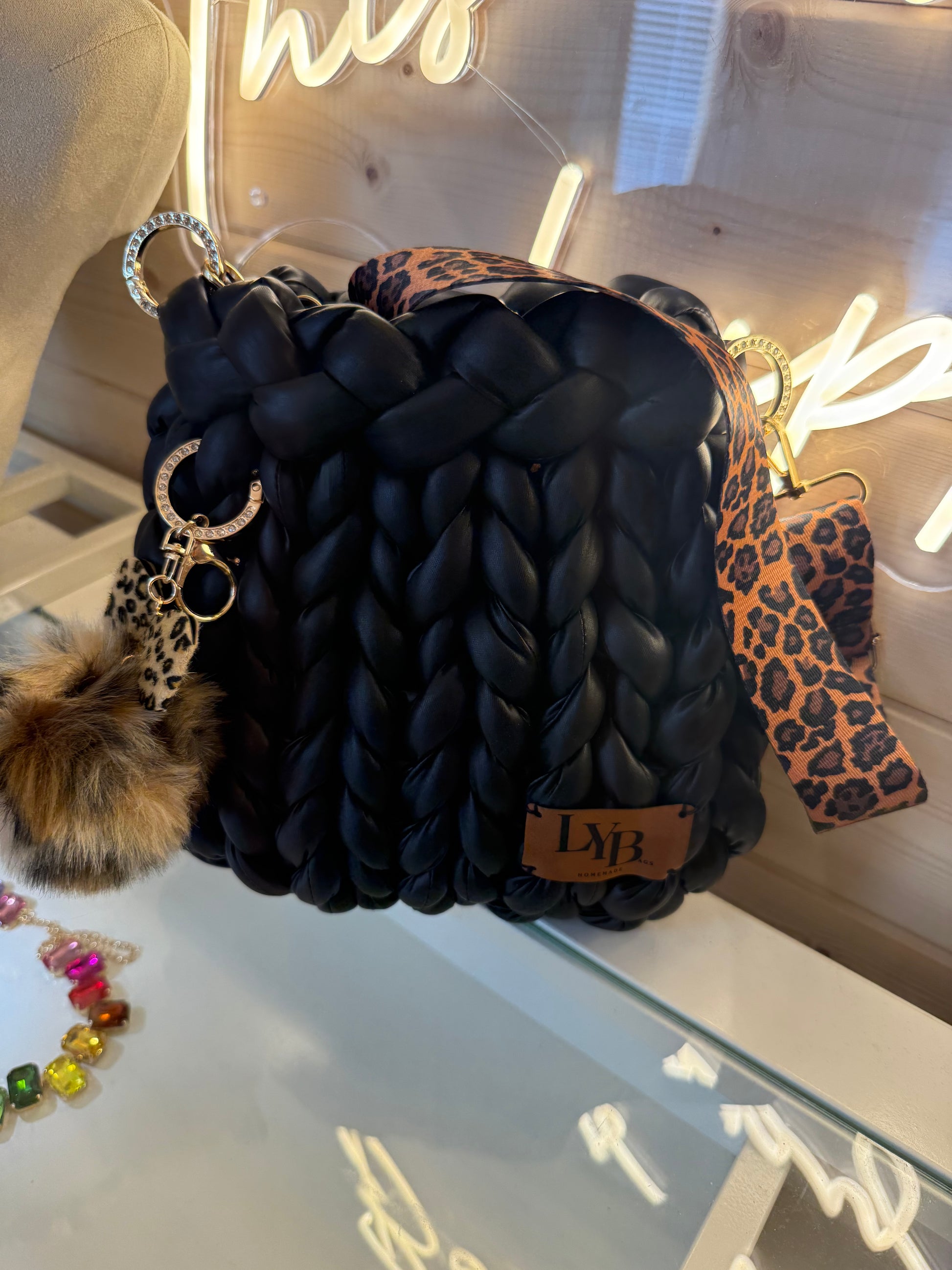 Wild at heart chunky braid faux leather bucket bag front view showing matte black braid texture with leopard st