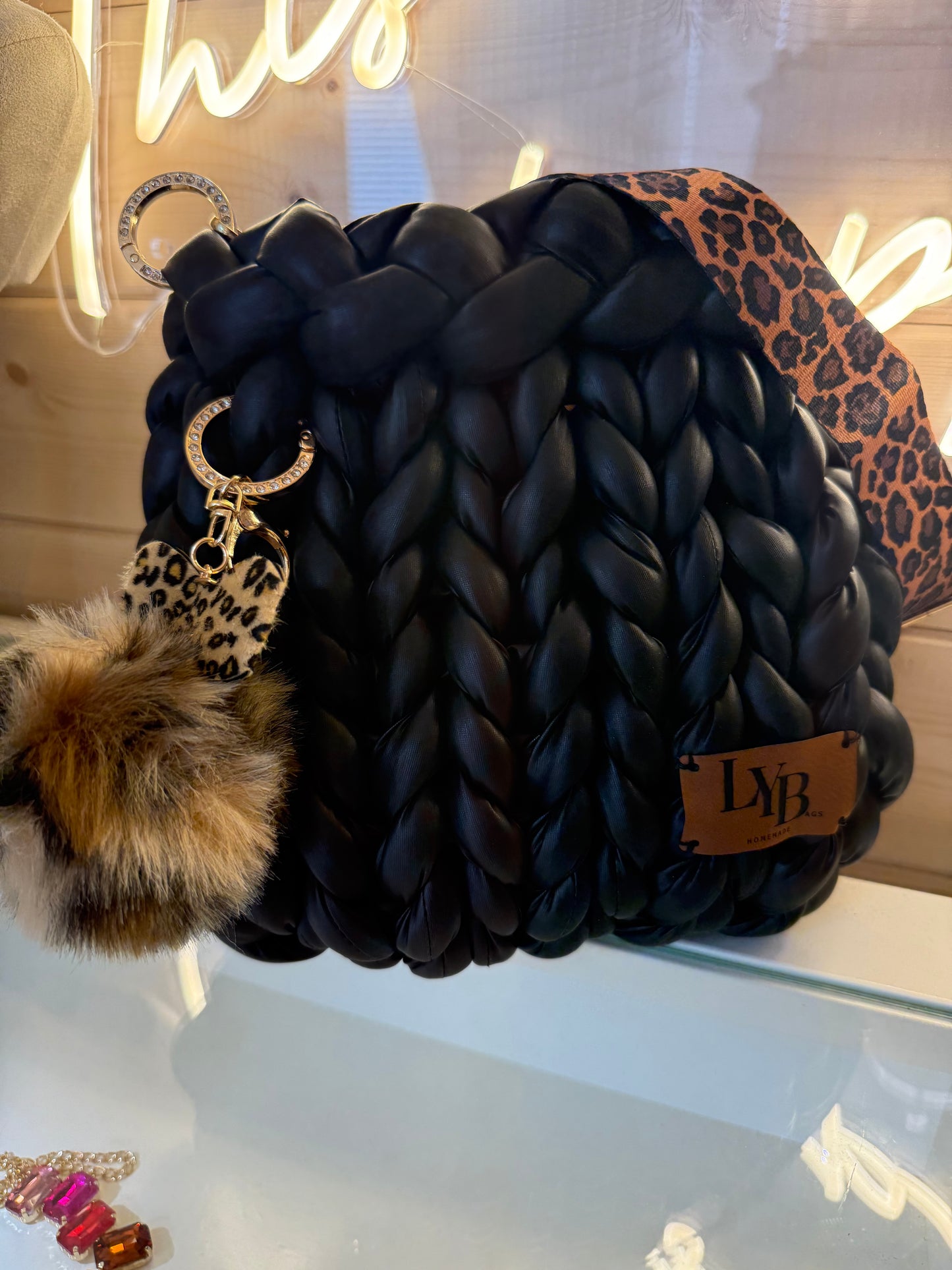 Wild at heart chunky braid faux leather bucket bag side view showing leopard print heart charm and faux fur pom pom