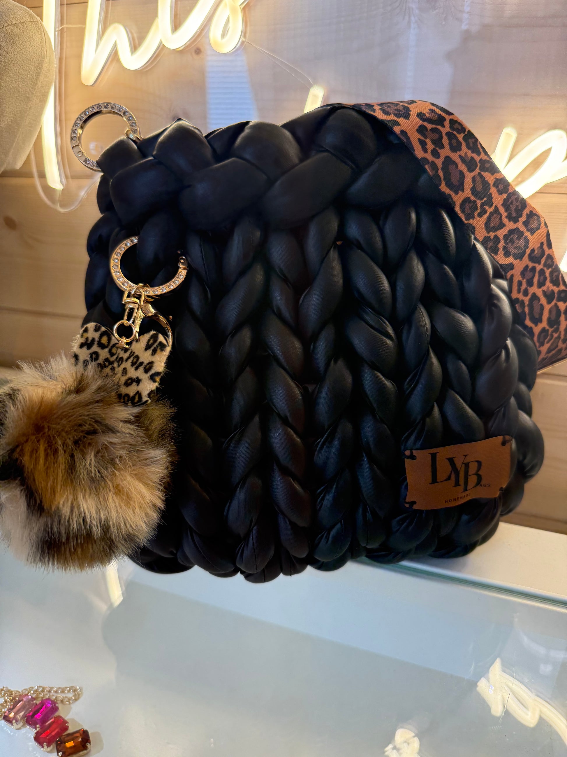Wild at heart chunky braid faux leather bucket bag side view showing leopard print heart charm and faux fur pom pom