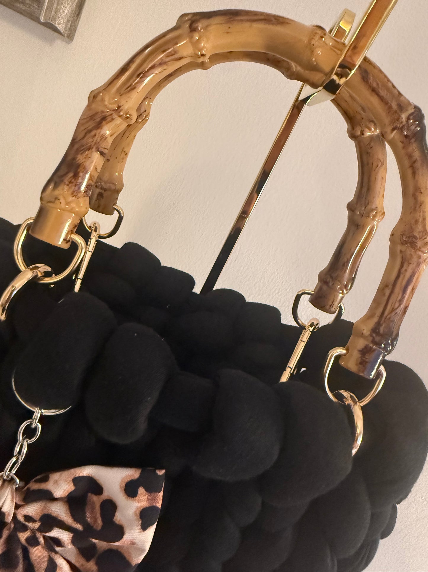 Close-up of lacquered bamboo top handle with gold-tone ring hardware on Chloe black chunky braid bag