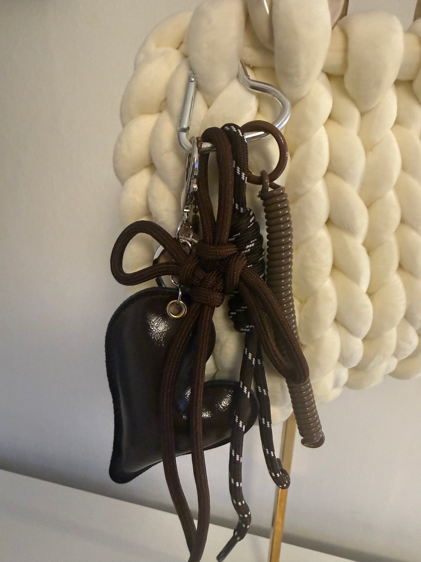 Close-up of detachable charm cluster on Pola bag featuring leather bow, knotted rope and ribbed tassel