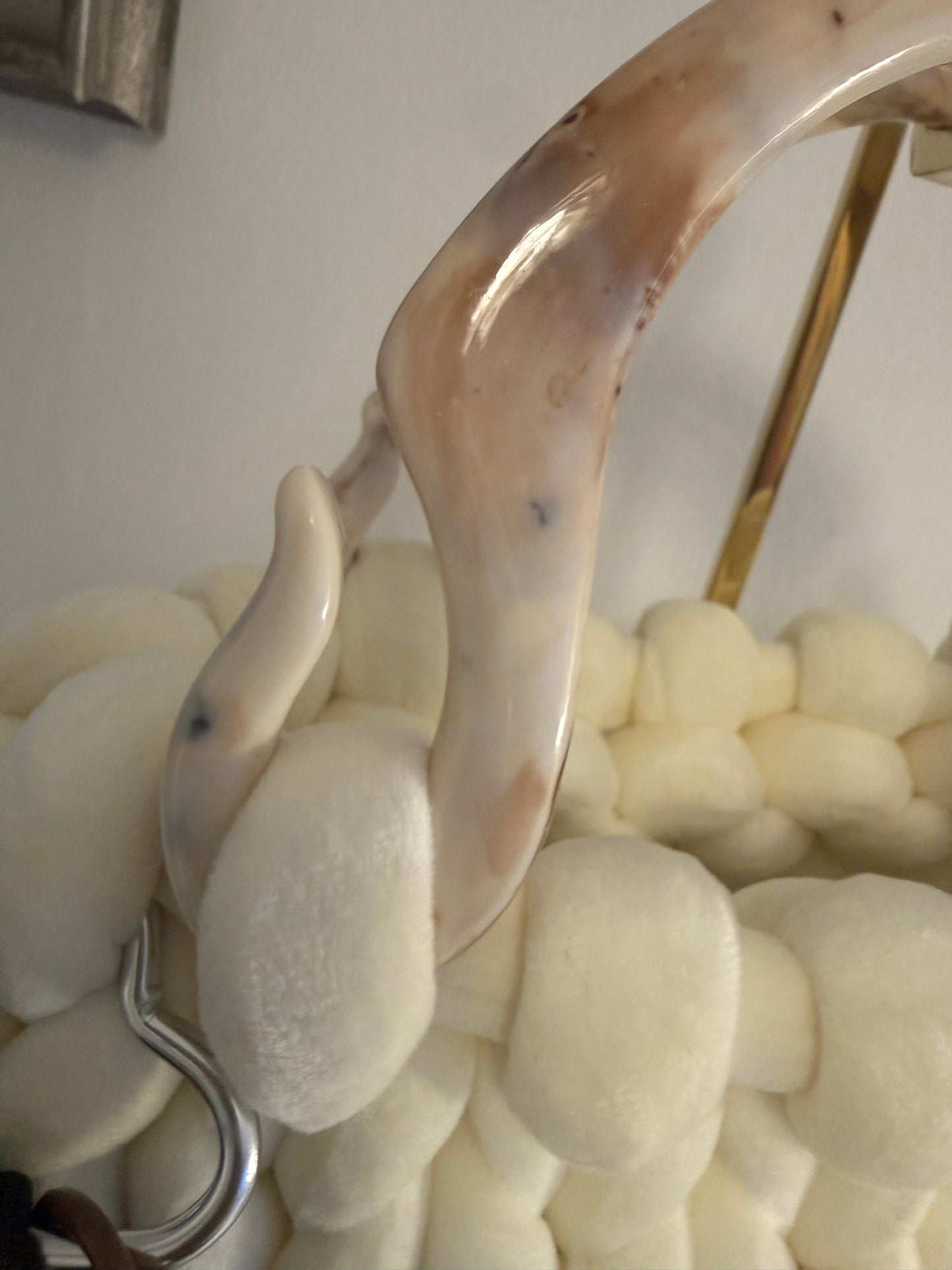 Close-up of marbled ivory acrylic top handle on Pola cream chunky knit luxury handbag
