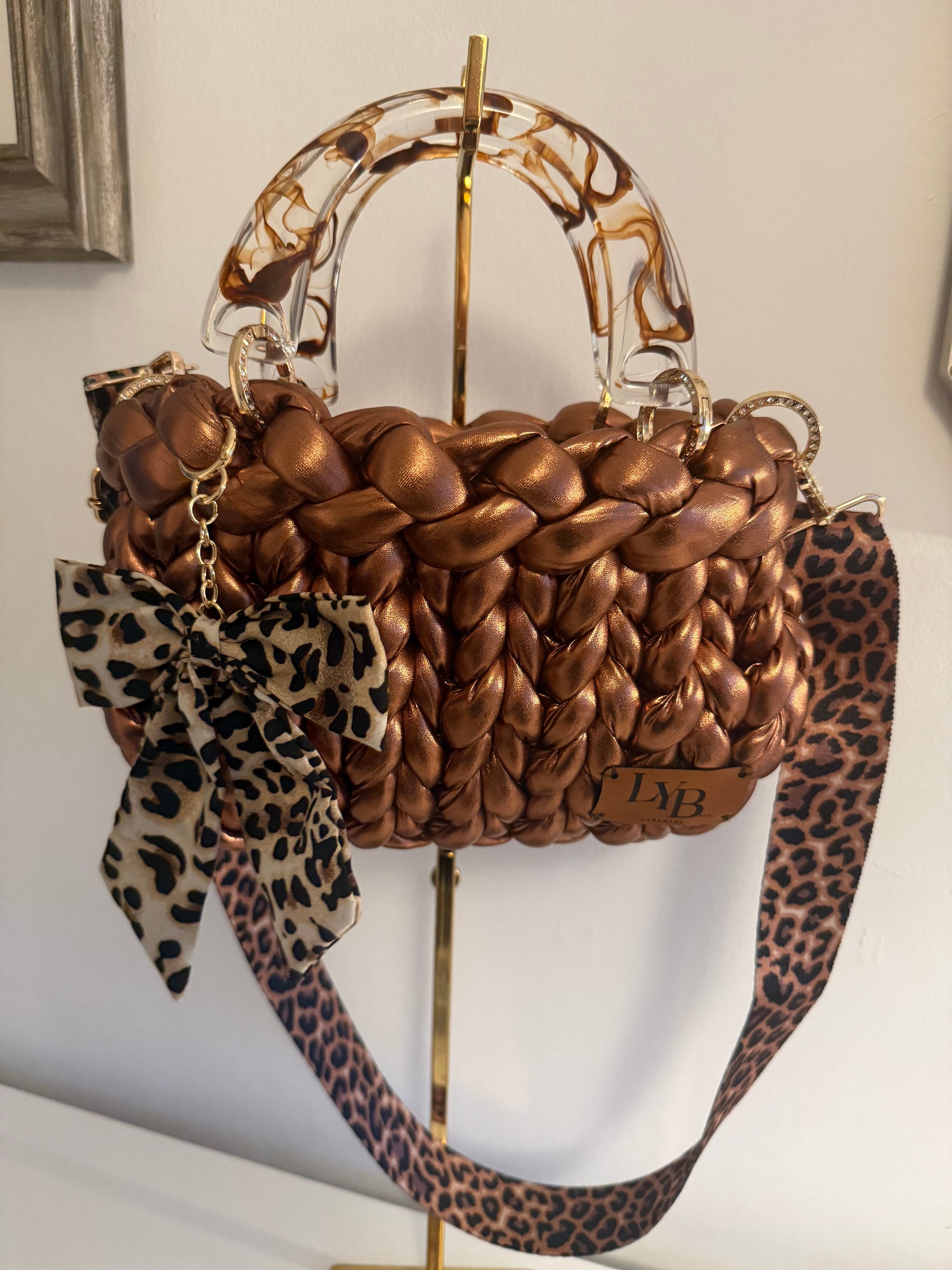 Rustica metallic bronze chunky braid bag with marbled acrylic handle, leopard bow and crossbody strap - front view