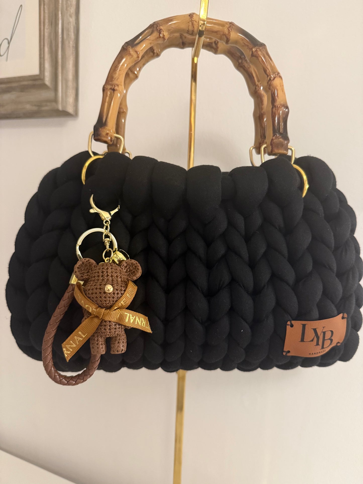 Nightlife black chunky braid bag with bamboo handle and woven teddy bear charm with gold hardware - front view