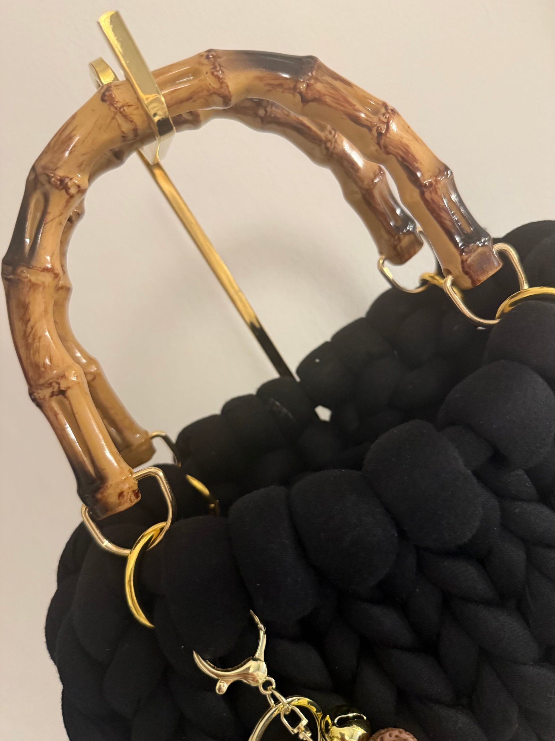 Close-up of lacquered bamboo top handle with gold-tone ring hardware on Nightlife black chunky braid bag