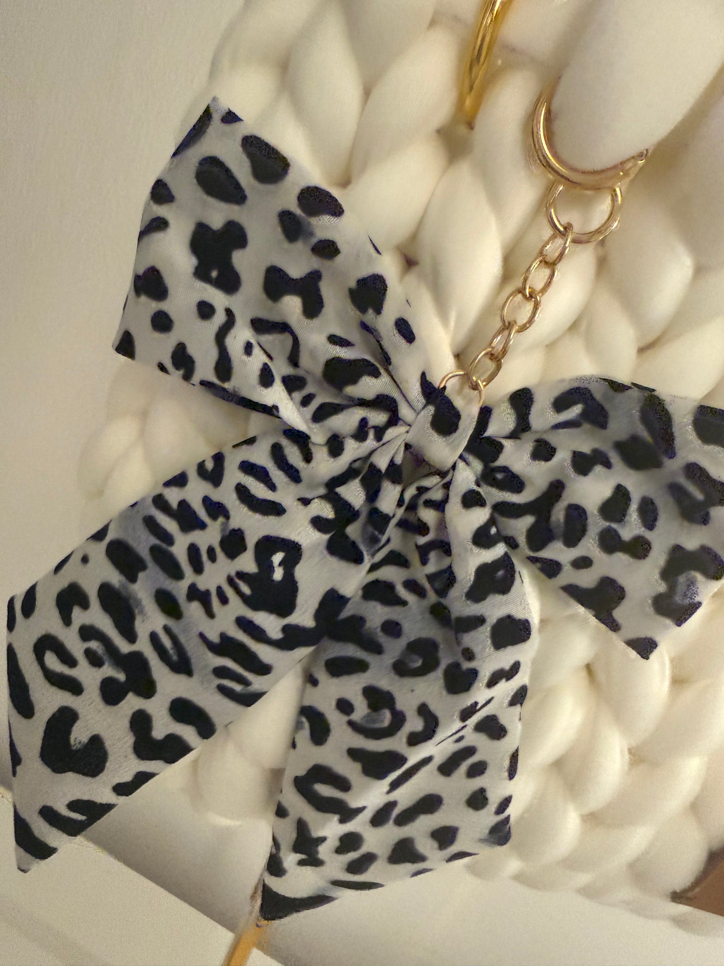 Close-up of detachable monochrome leopard print chiffon bow charm on gold chain on Blanca white bag