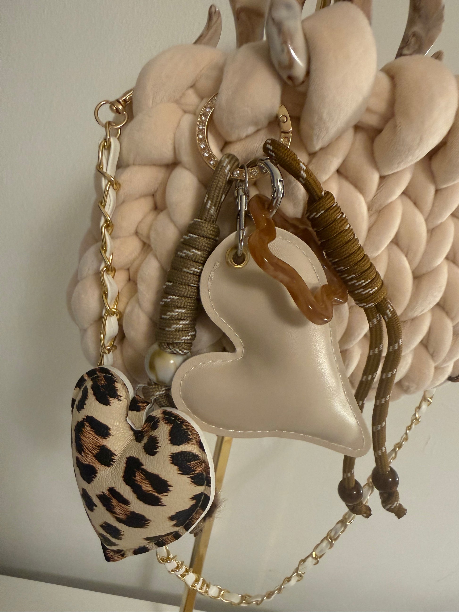 Close-up of detachable double heart charm cluster featuring cream leather heart and leopard print heart on gold rope cord