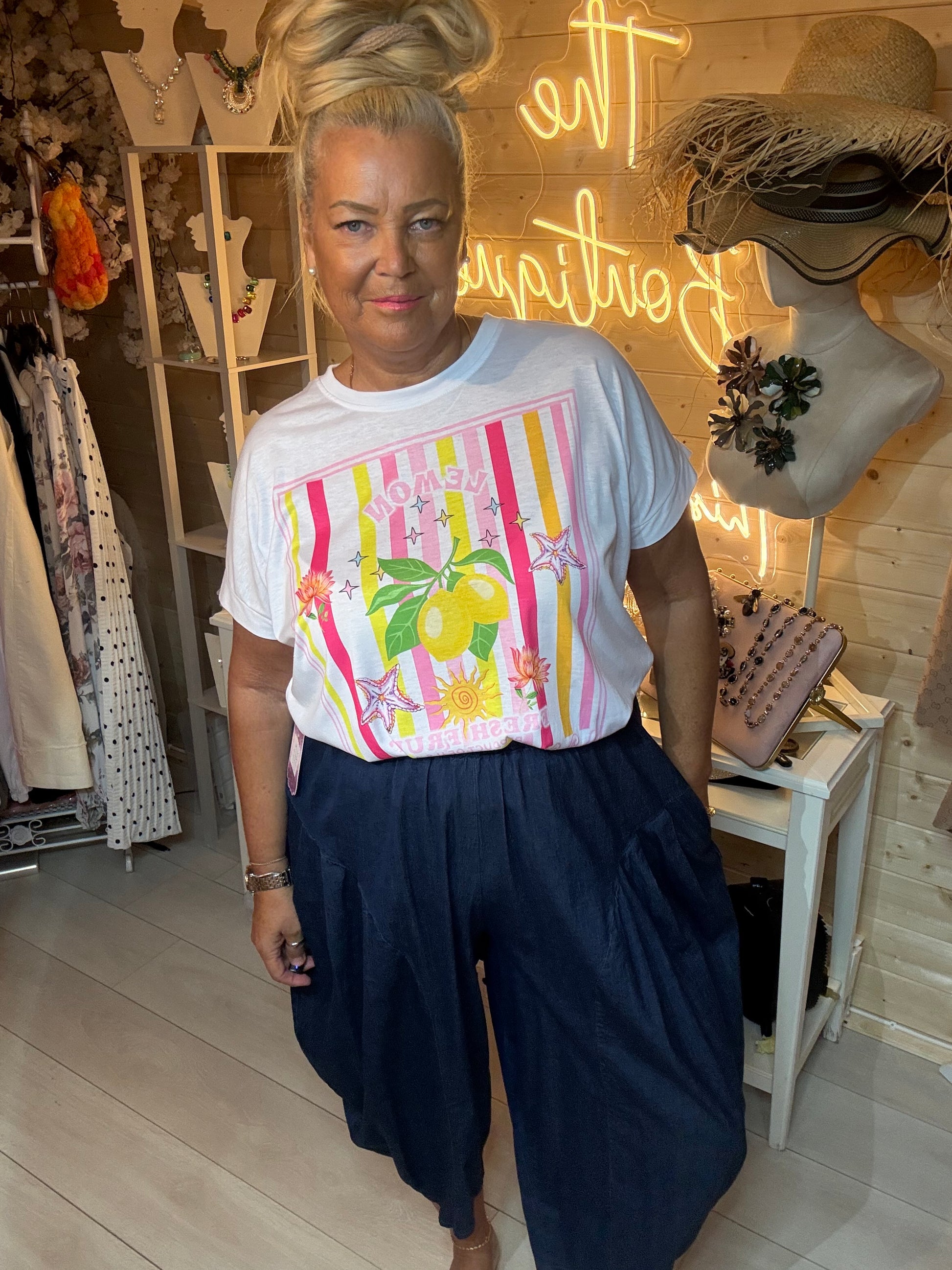 Woman wearing Limone white lemon graphic t-shirt with dark denim slouch trousers in boutique