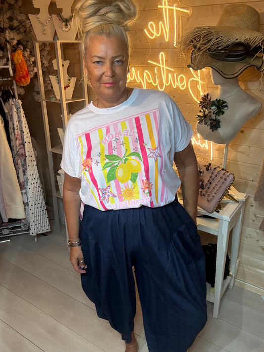 Woman wearing Limone white lemon graphic t-shirt with dark denim slouch trousers in boutique