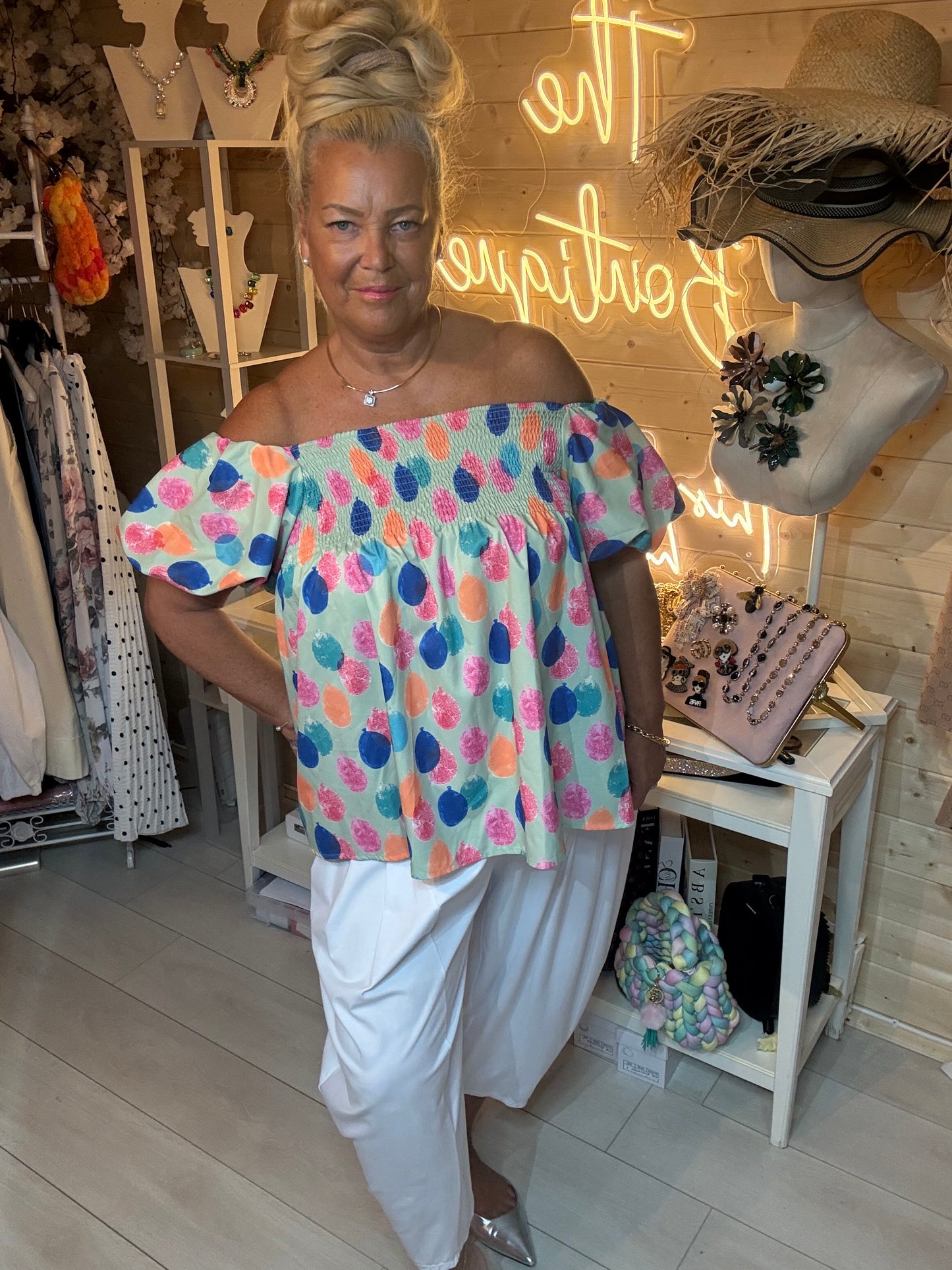 Woman wearing Sorbet mint green off-shoulder smocked bardot top with white wide-leg trousers – front view