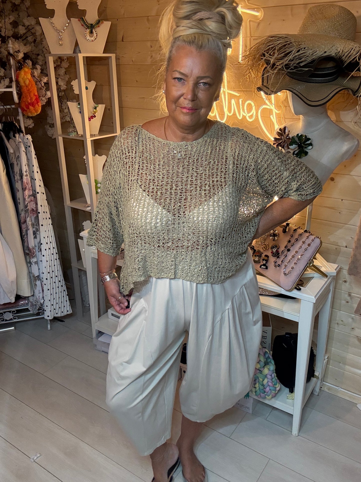 Woman wearing Mesh orange open weave knit top with grey harem trousers – boutique front view