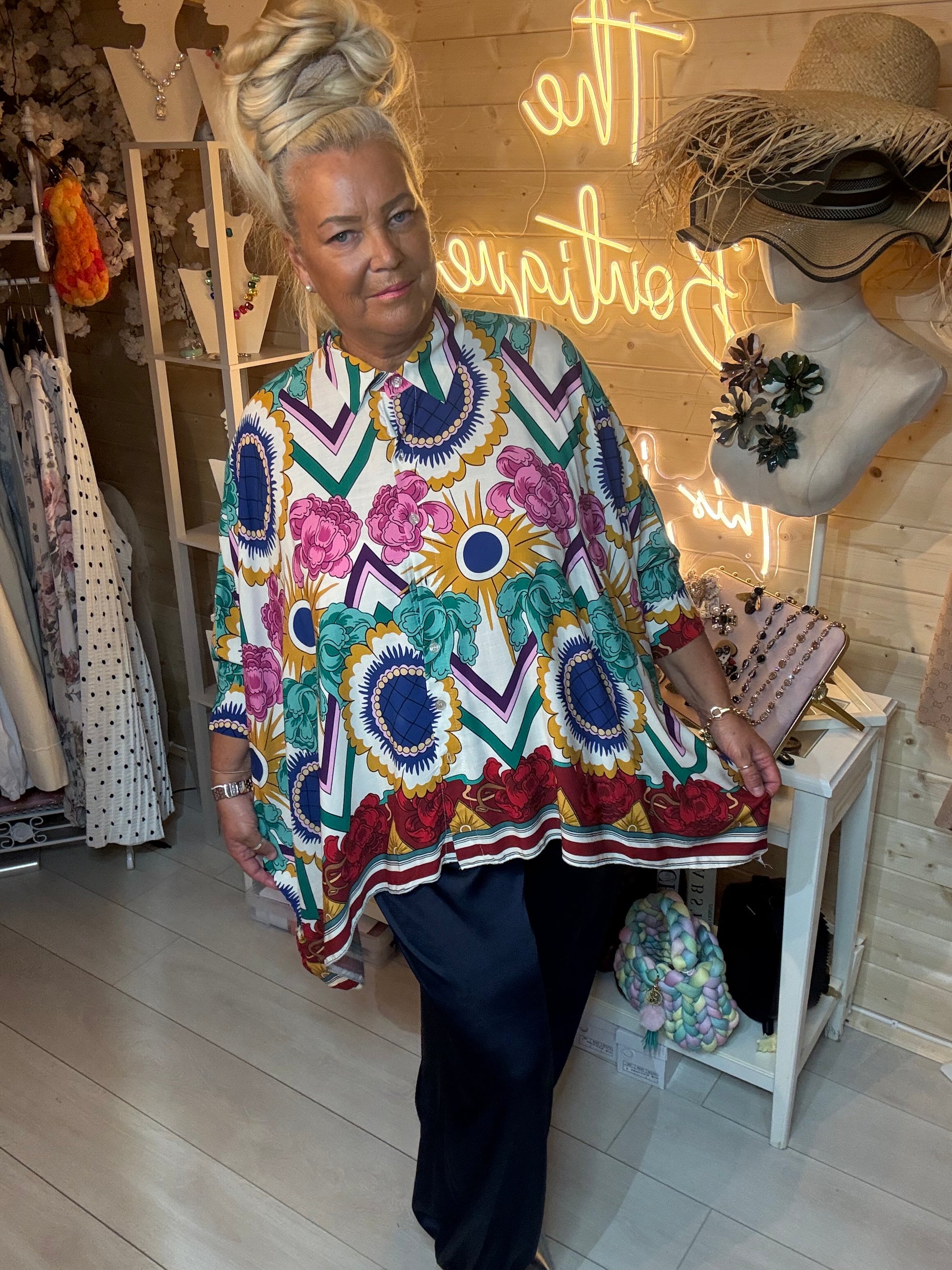 Woman wearing Baroque bold floral chevron print oversized shirt with navy harem trousers – boutique front view