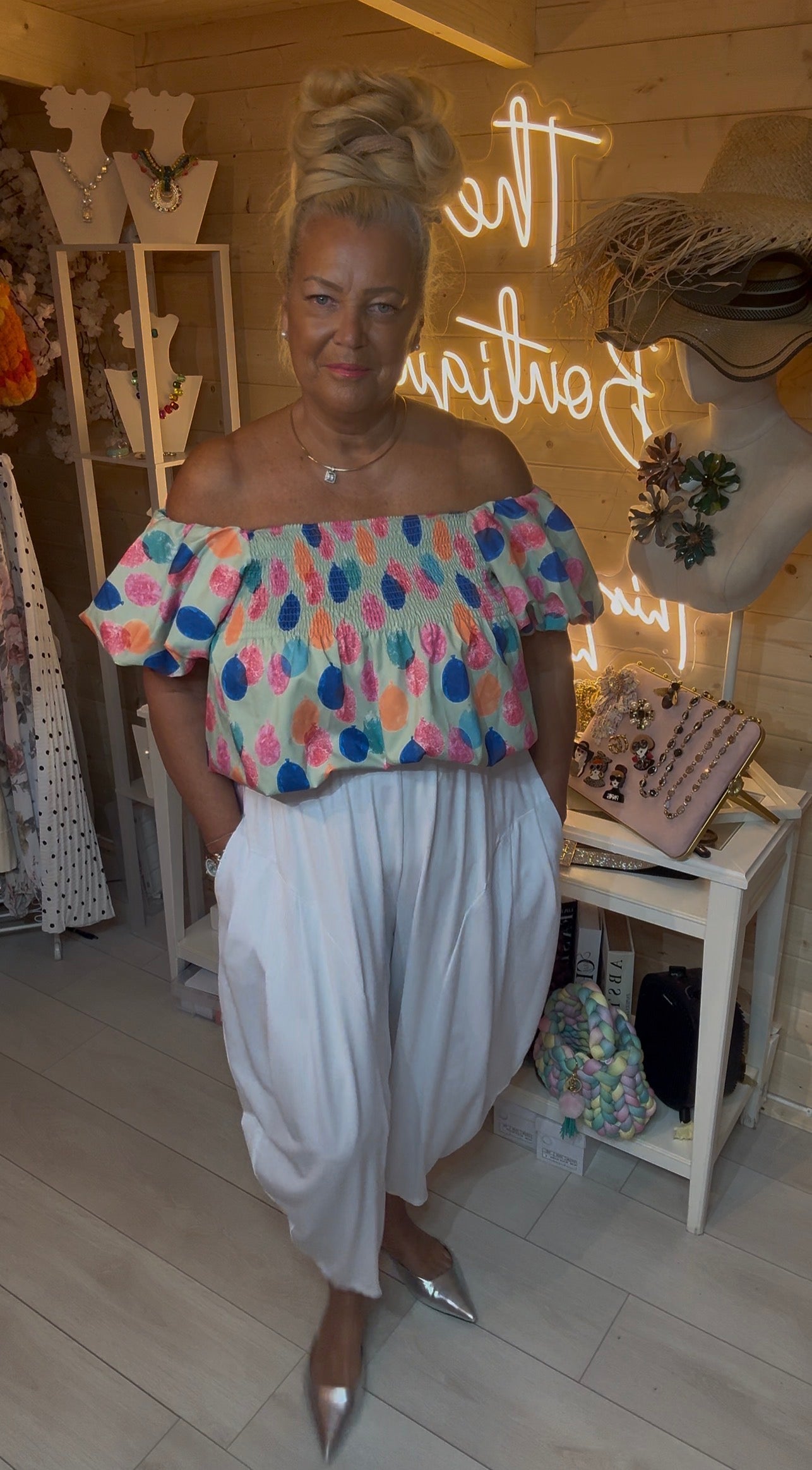 Sorbet fruit-dot print bardot top full length with white wide-leg trousers and silver mules