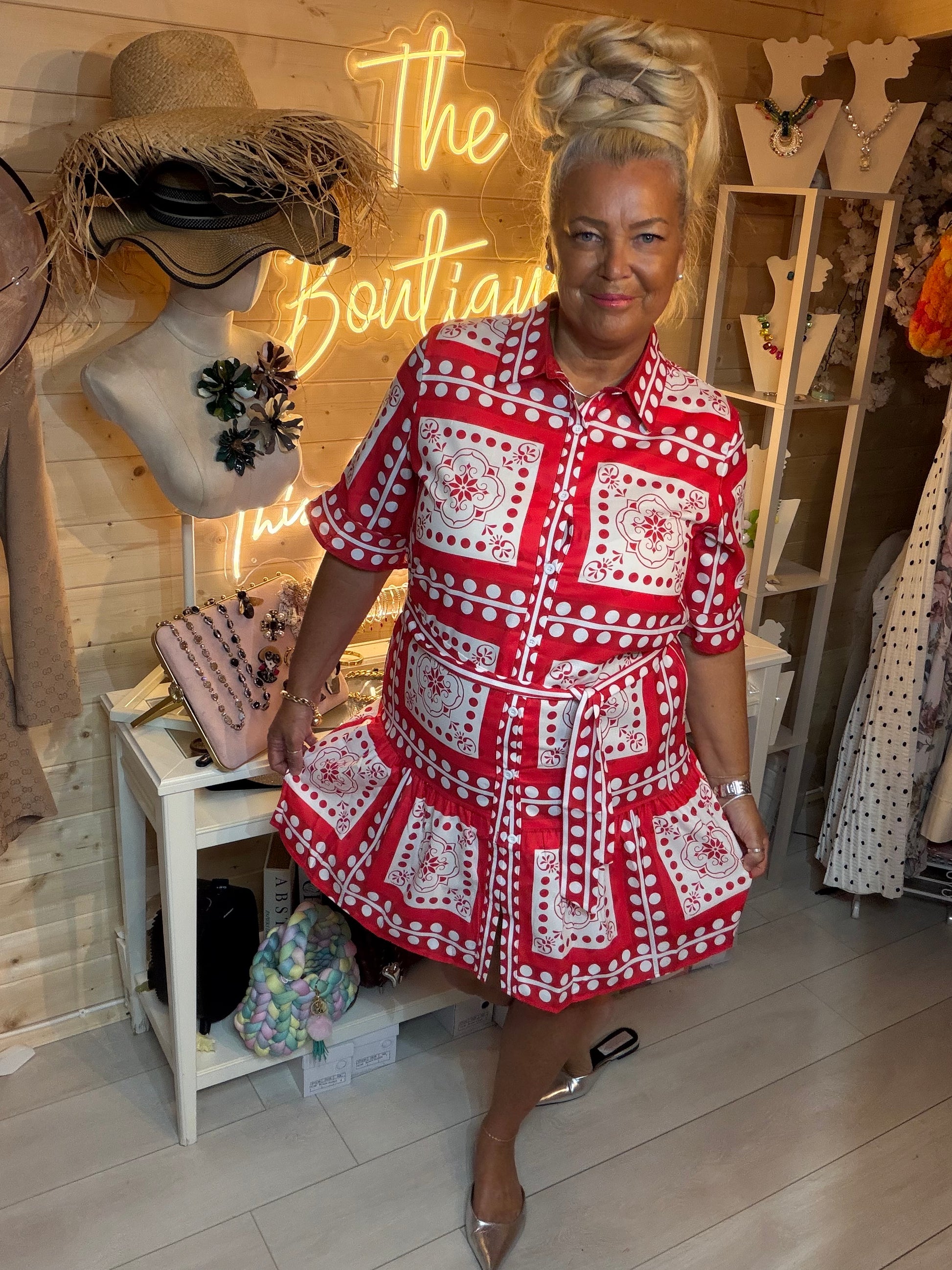 Woman wearing Sicilia red and white tile print shirt dress belted at waist – boutique front view with silver mules