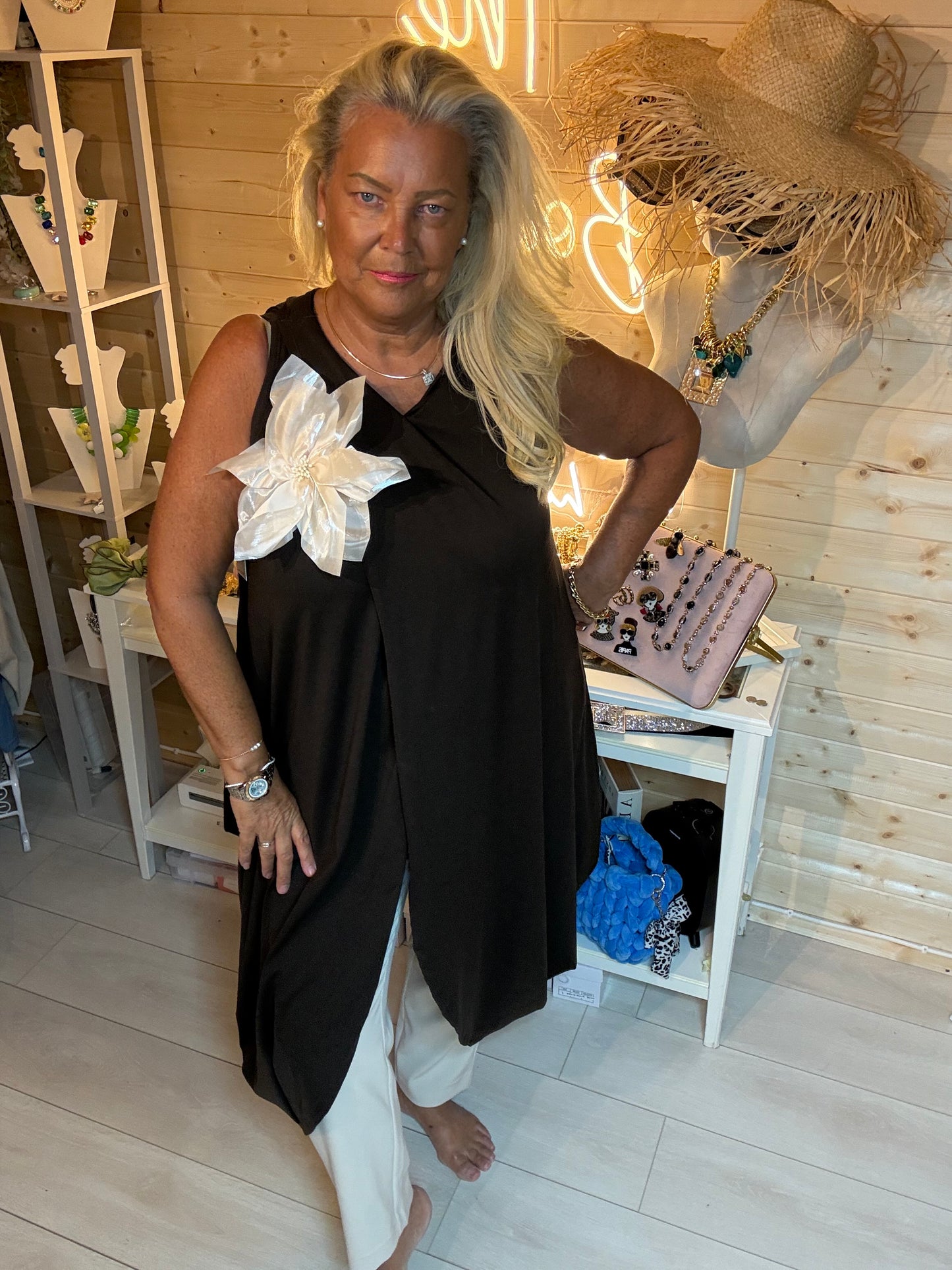 Fleur Asymmetric Wrap Slit Tunic Top with Detachable Cream Flower Corsage in Black - styled with white trousers - One Size 8-20 - The Ultimate Ladies Boutique