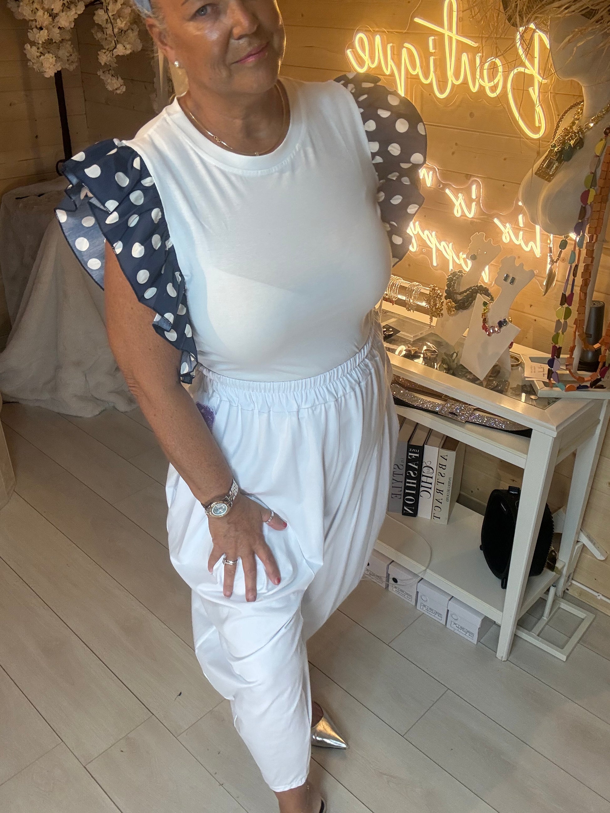 Dotty white top with navy polka dot ruffle sleeves – full length side view on model