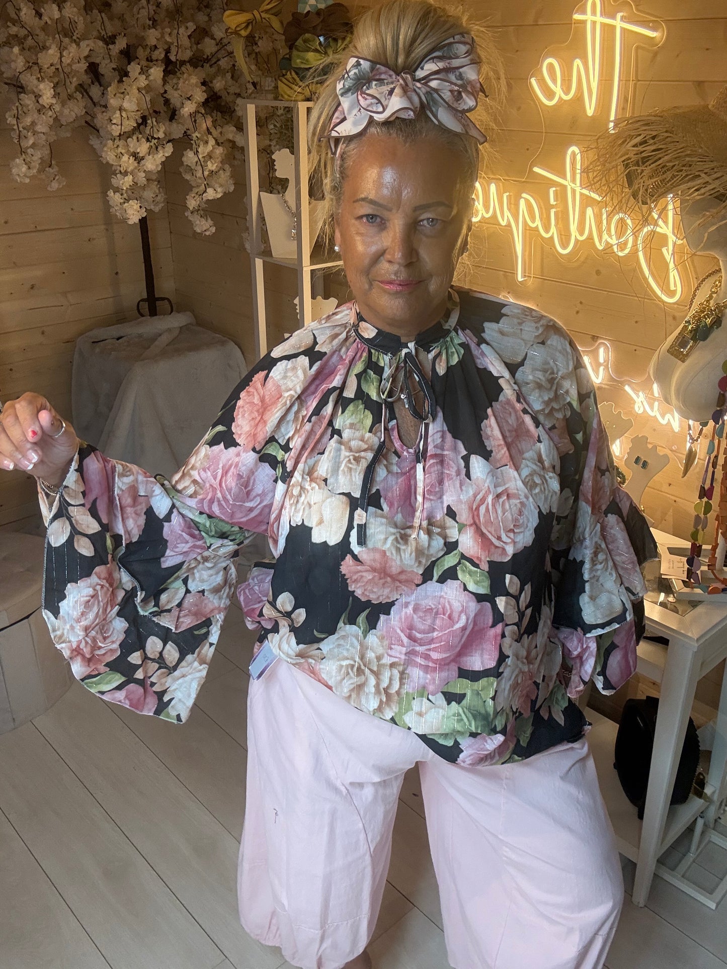Valentina black floral ruffle blouse front view on model styled with white trousers – The Ultimate Ladies Boutique