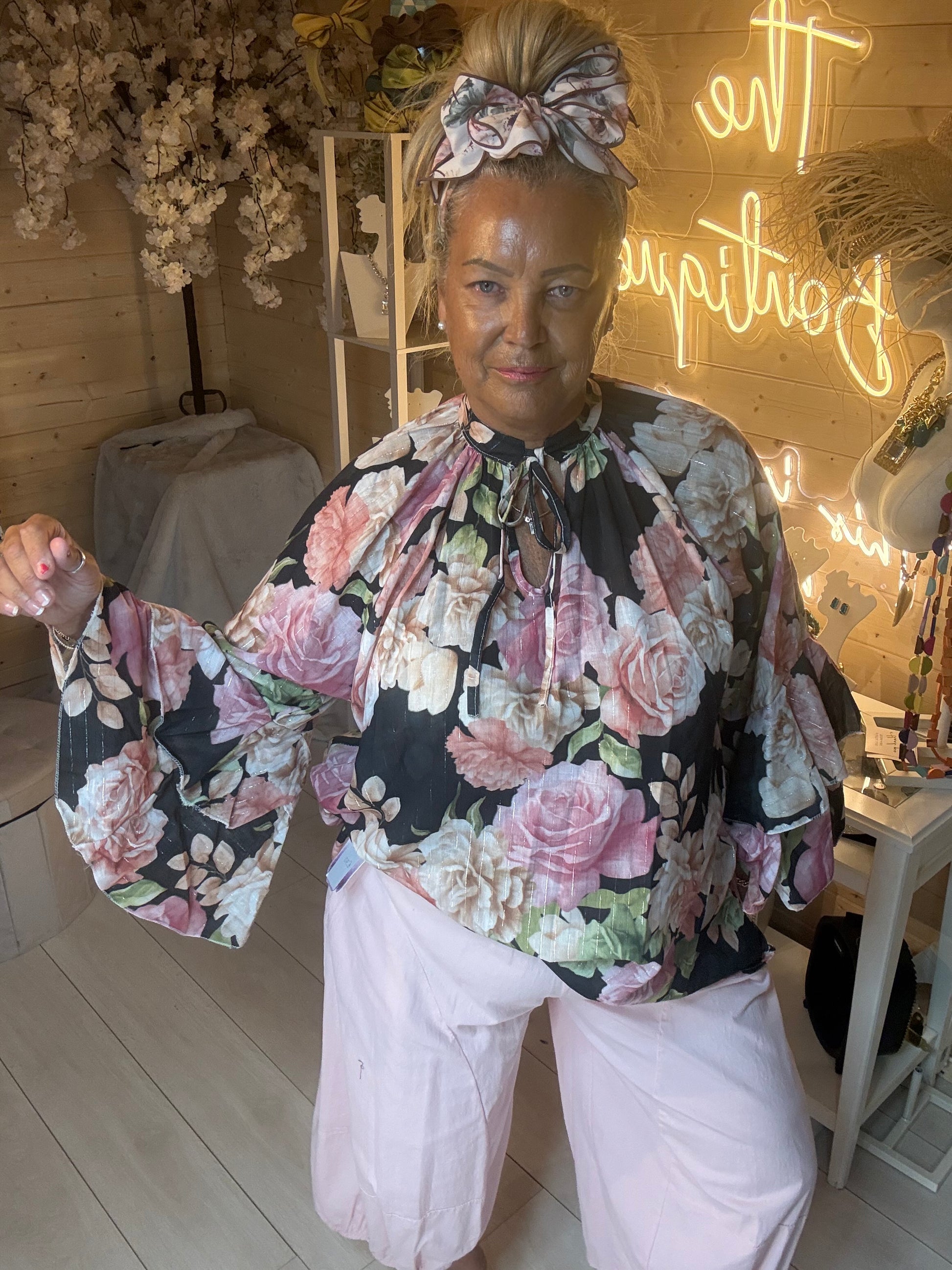 Valentina black floral ruffle blouse front view on model styled with white trousers – The Ultimate Ladies Boutique
