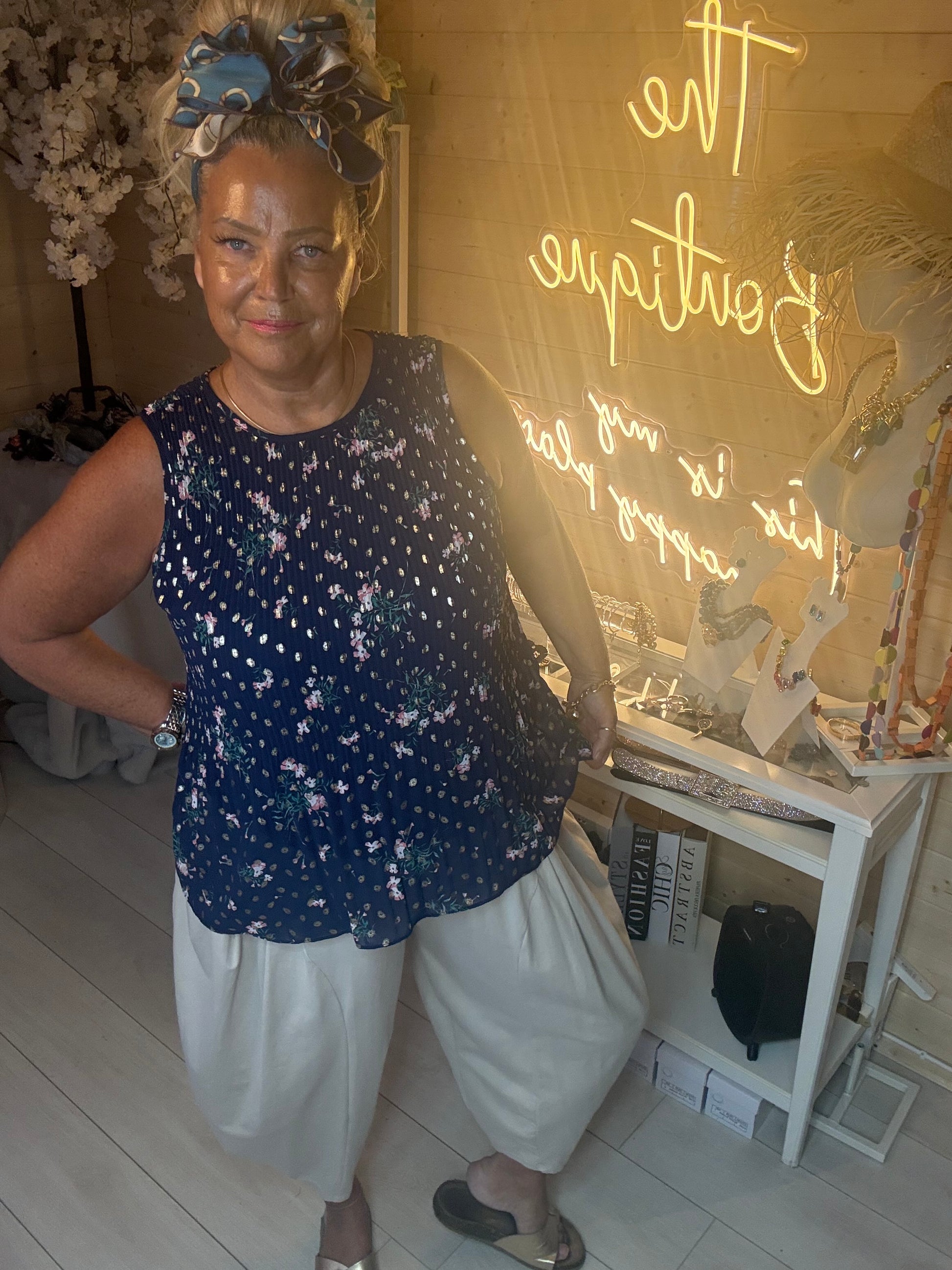 Woman wearing Capri Navy Floral Crinkle Sleeveless Top styled with stone slouch trousers in The Ultimate Ladies Boutique