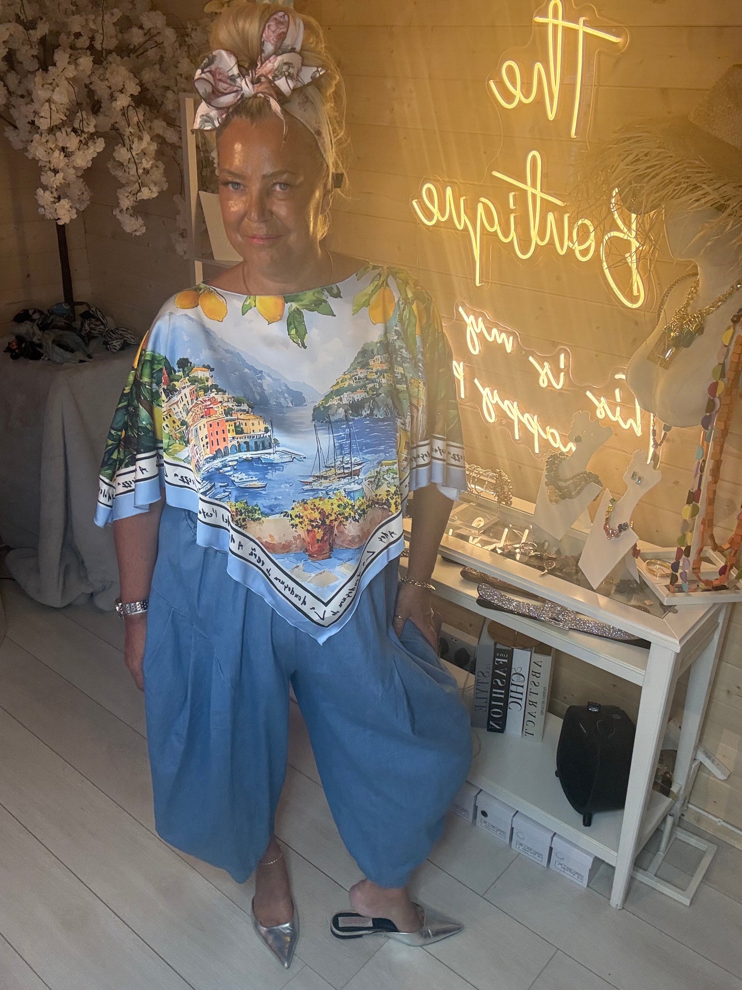 Amalfi Poncho Top full length view showing Italian scenic print with light denim trousers and silver heels