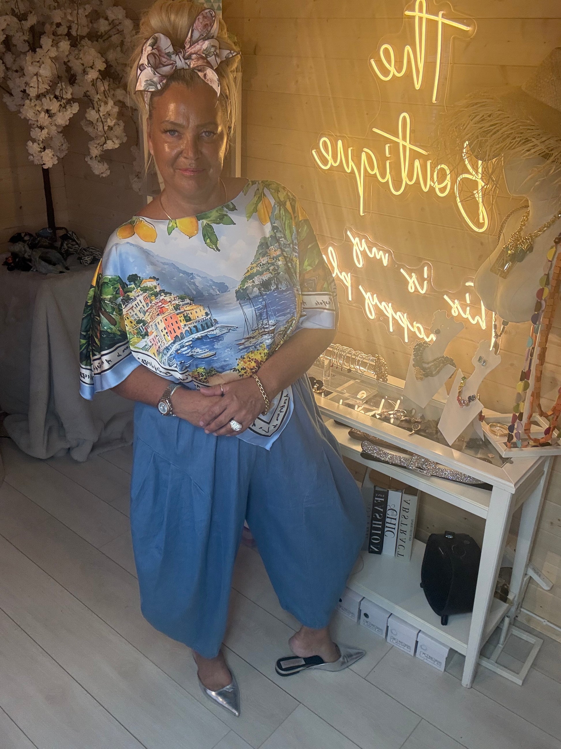Amalfi Poncho Top styled with plain light denim trousers and silver pointed heels boutique setting