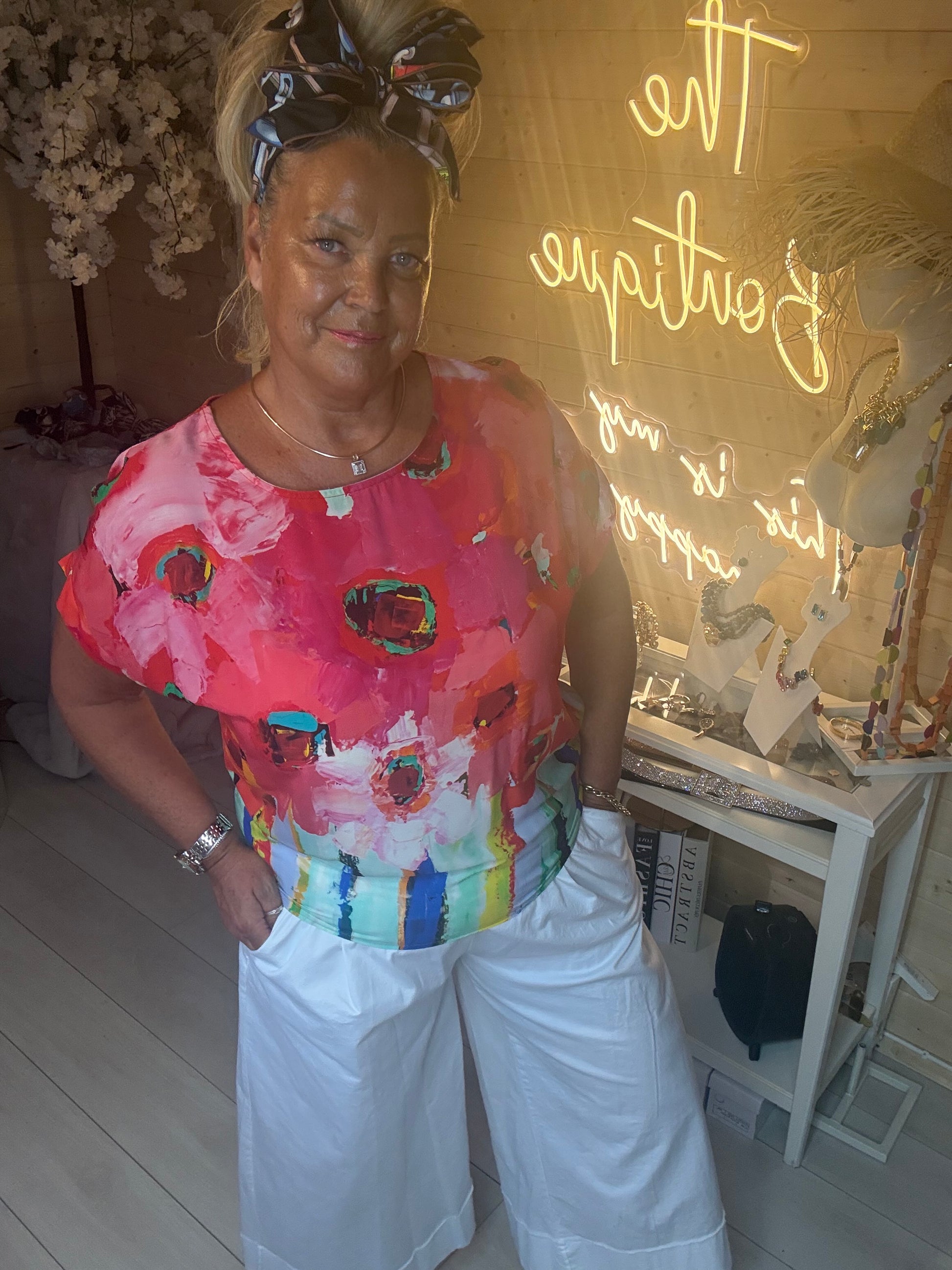 Model wearing Sorento Coral Abstract Floral Poncho Top with coral harem trousers showing relaxed poncho silhouette