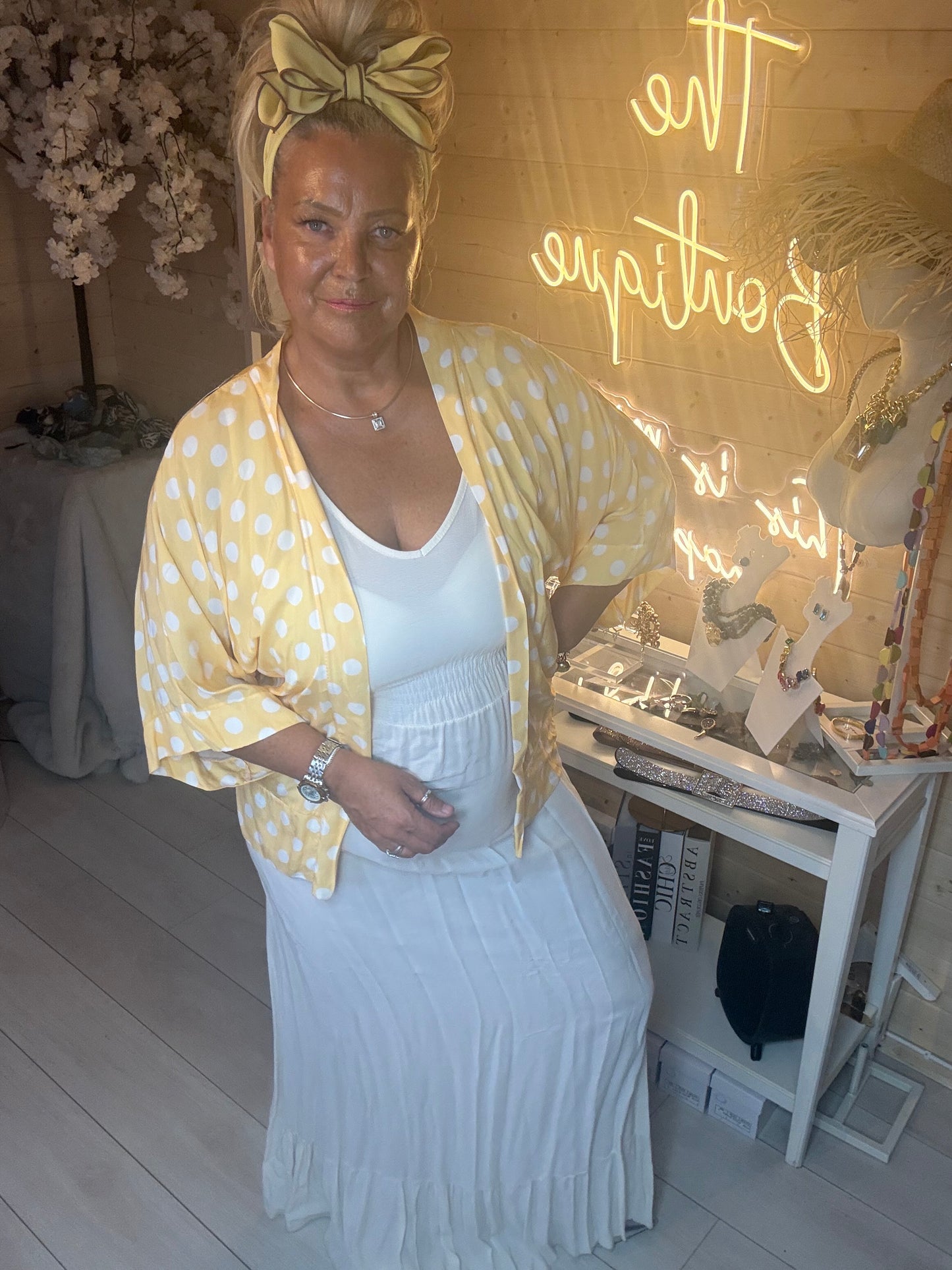 Close up of model wearing white ribbed maxi dress with yellow polka dot shawl showing scoop neckline and smocked waist detail
