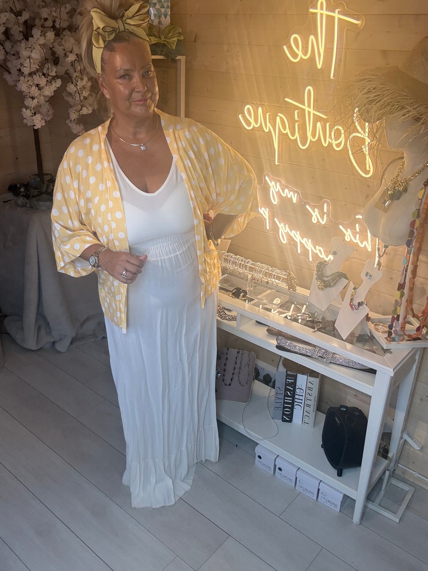 Full length view of white ribbed maxi dress with tiered ruffle hem and yellow polka dot shawl draped over shoulder