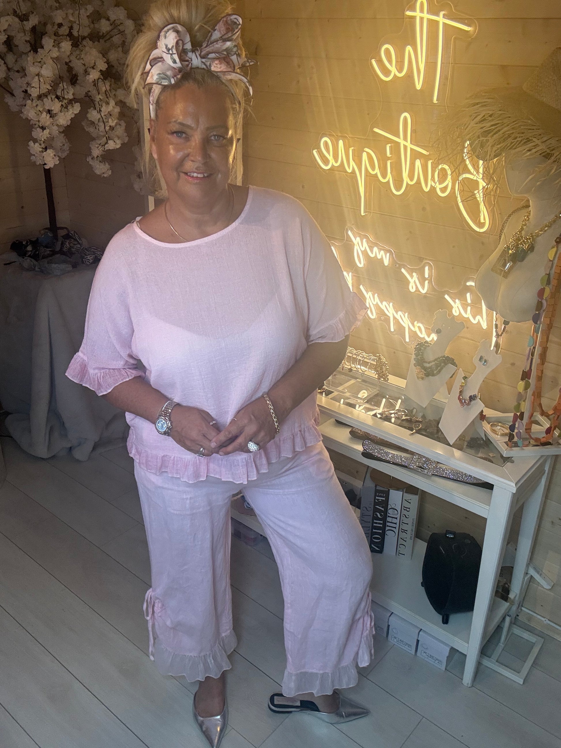 Model posing in Rosa Blush Pink Ruffle Hem Crinkle Top with pink ruffle linen trousers showing relaxed flattering fit one size 8-18