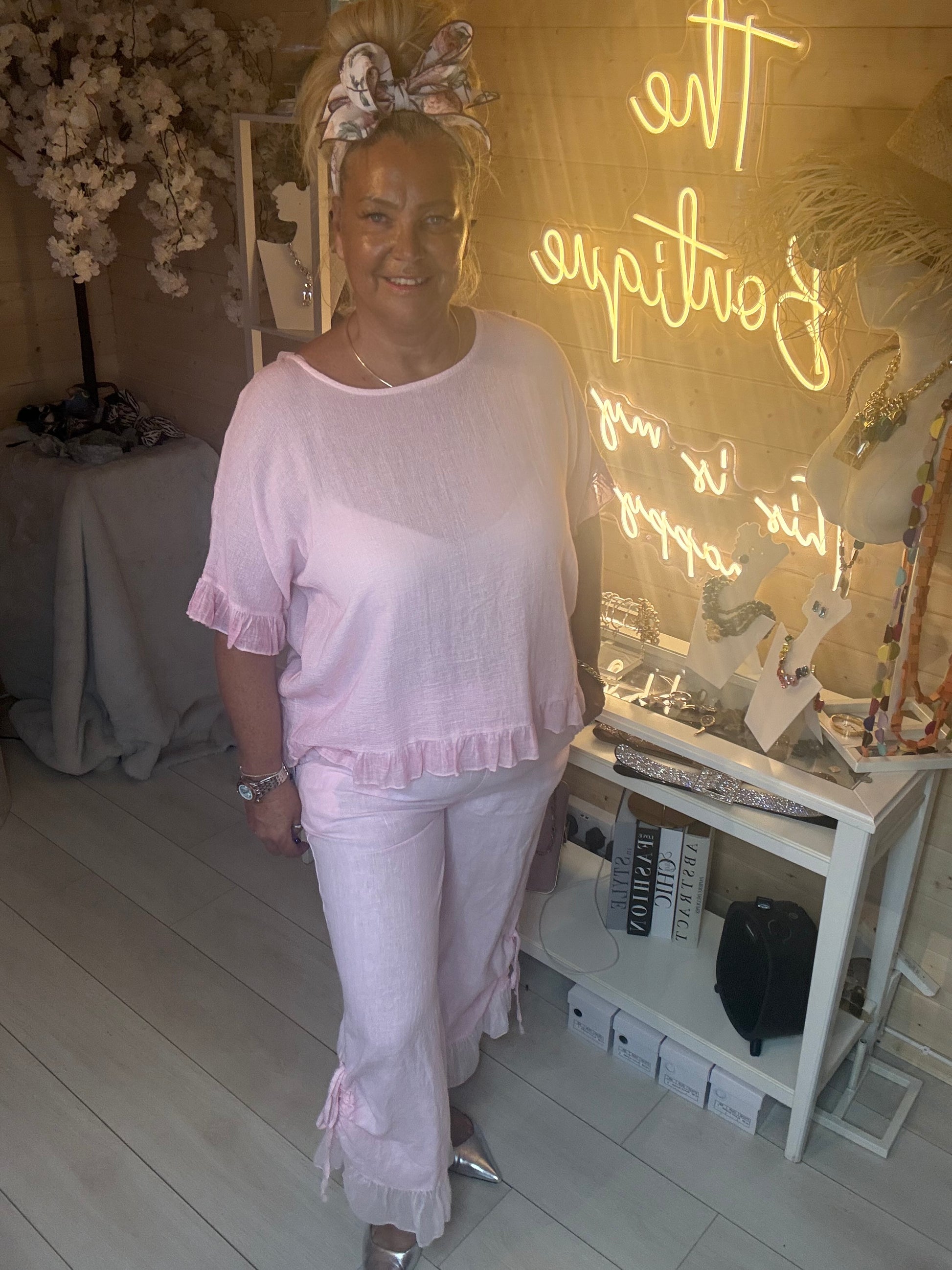 Model wearing Rosa Blush Pink Ruffle Hem Crinkle Top with pink ruffle hem linen trousers and silver pointed heels full length