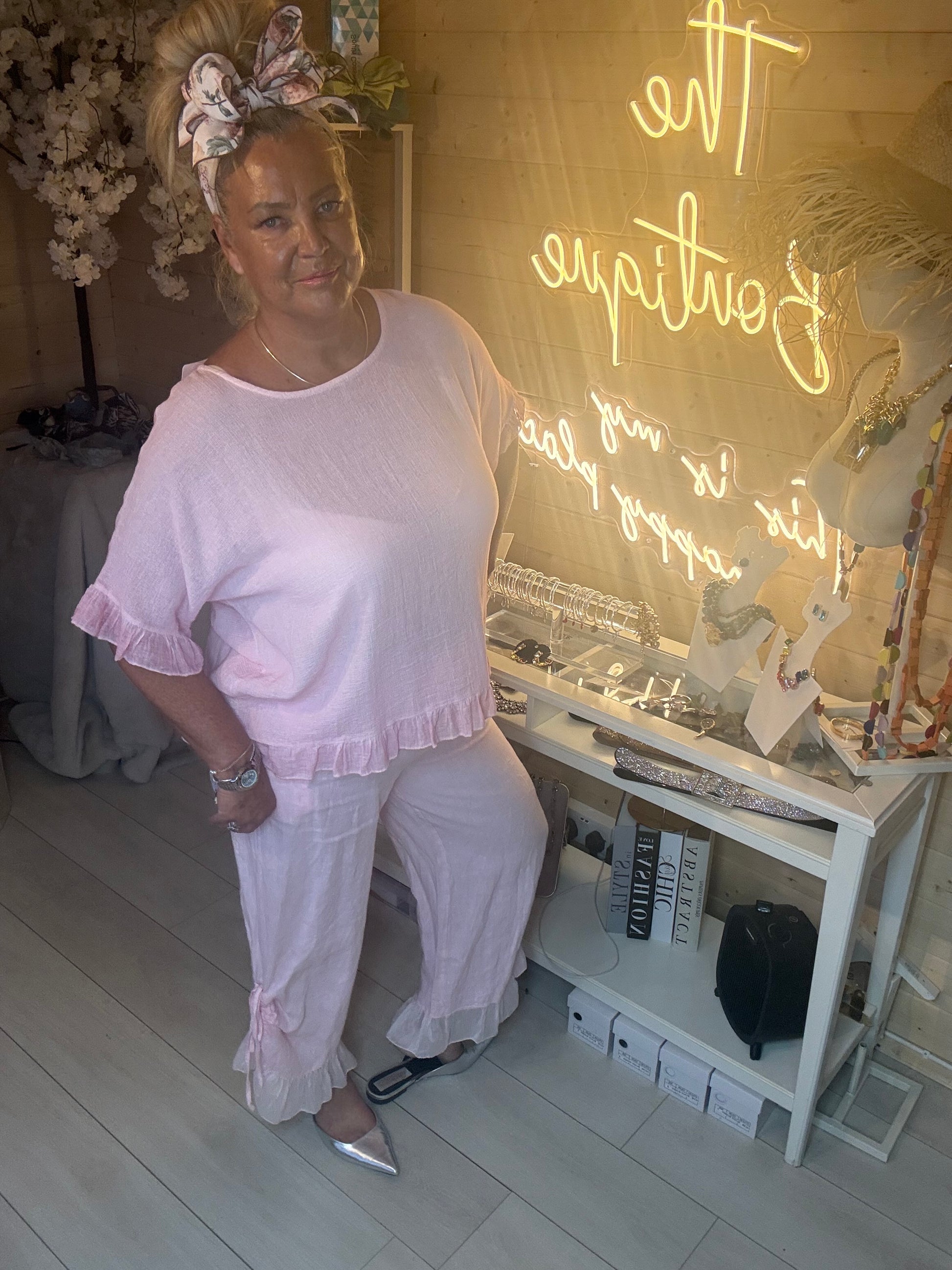 Rosa Blush Pink Ruffle Hem Crinkle Top styled with Sky Shimmer Ruffle Hem Linen Trousers in pink complete co-ord look boutique setting