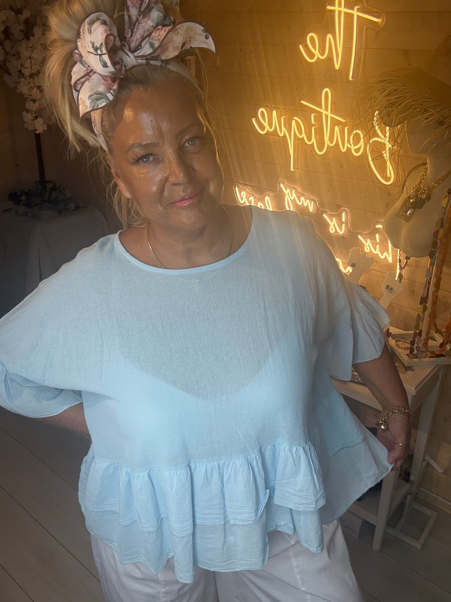 Close up of model wearing Sky Blue Tiered Ruffle Hem Top showing double tiered ruffle hem and linen fabric detail