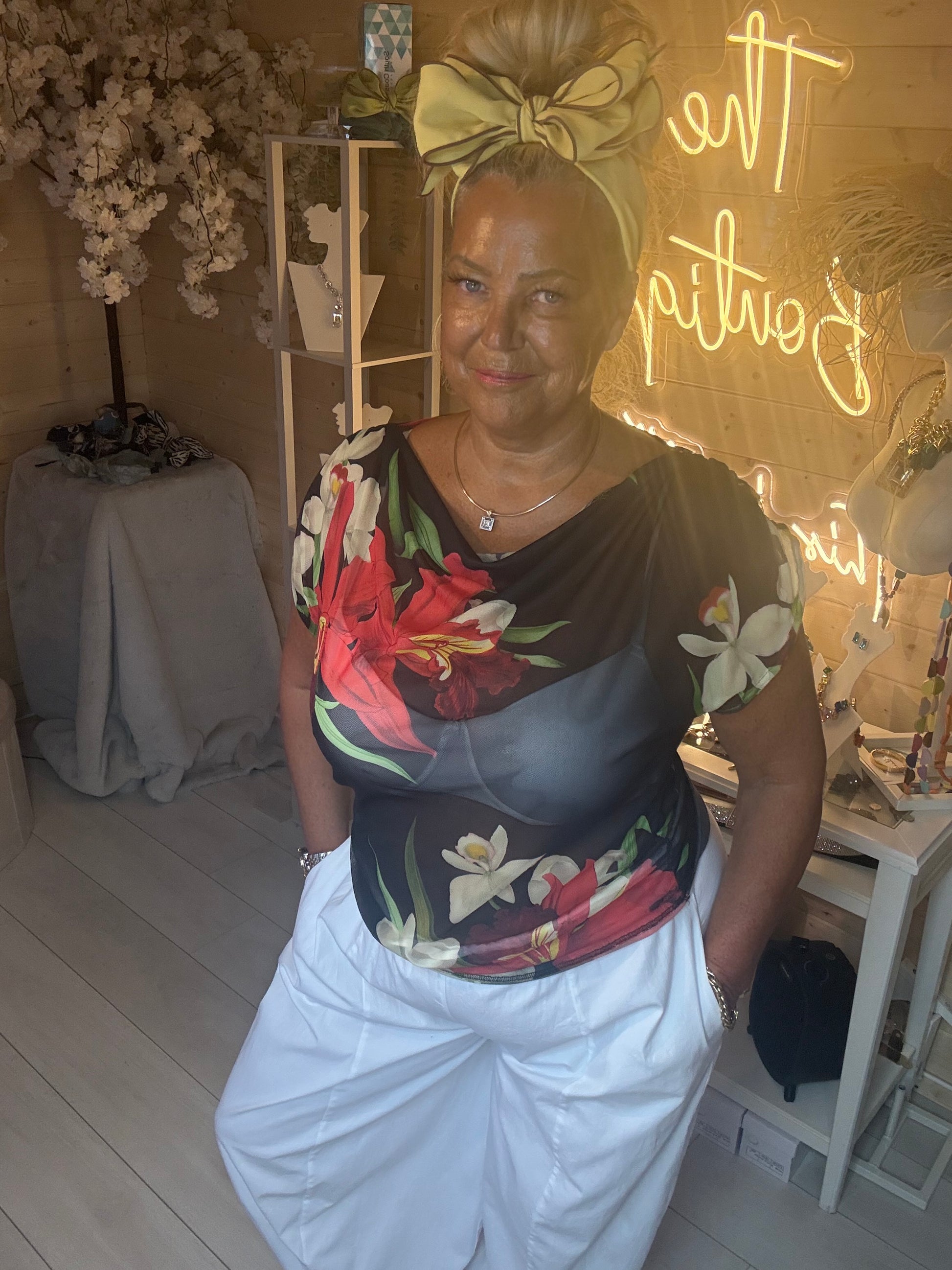 Close up of model wearing Tropea Dark Floral Satin Top showing red lily and white floral print detail on dark navy satin fabric