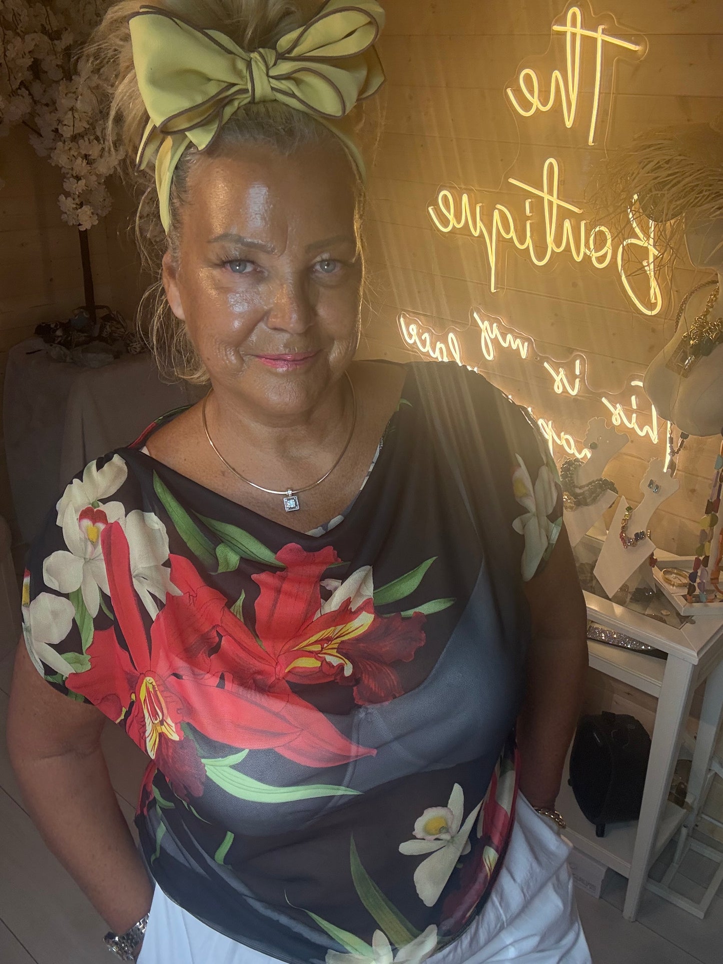 Close up portrait of model wearing Tropea Dark Floral Satin Top showing bold tropical floral print and soft draped satin neckline one size 12-20