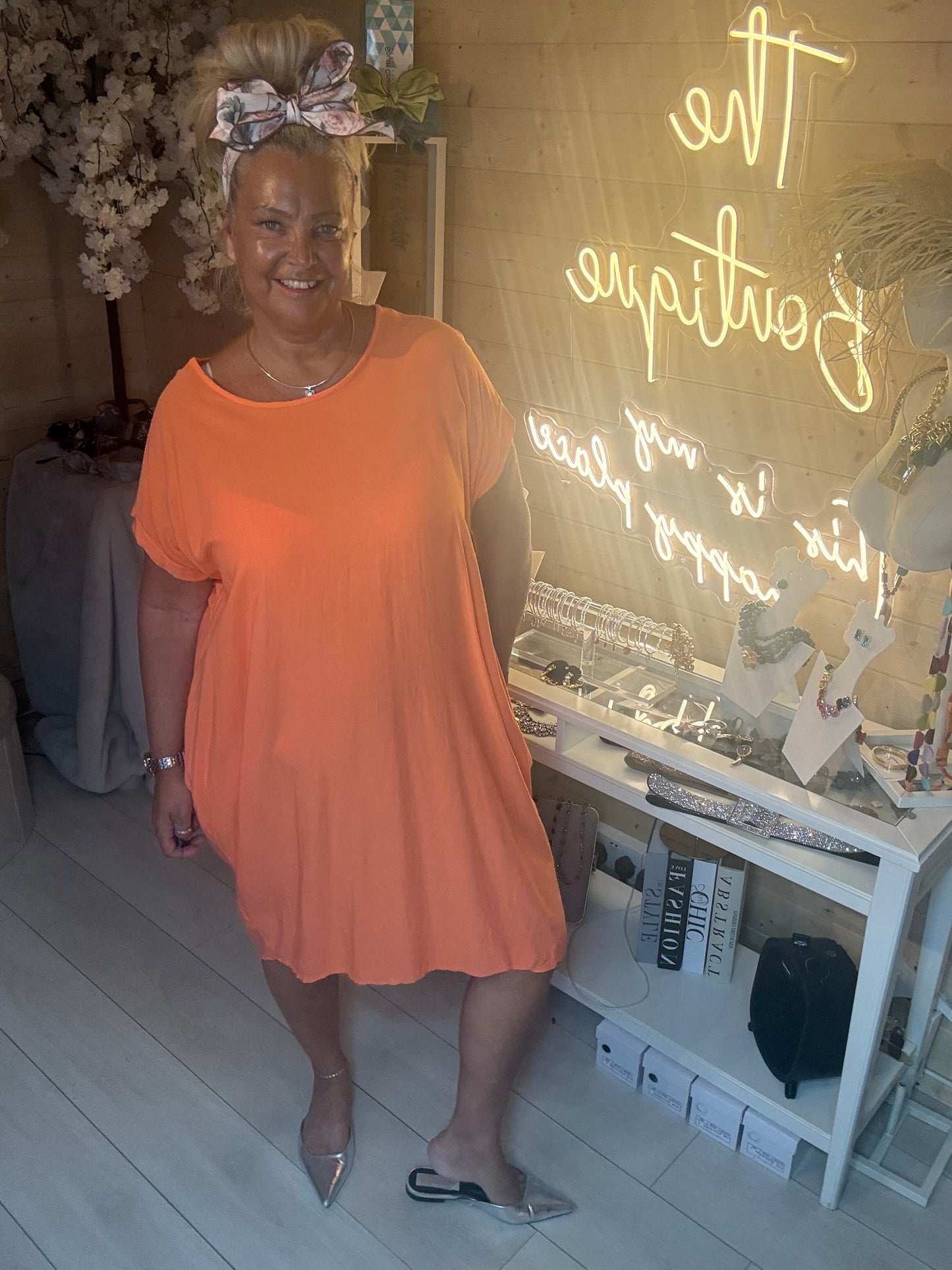 Model wearing Coral Cocoon Twist Back Jersey Dress showing relaxed cocoon silhouette with silver mule heels full length view