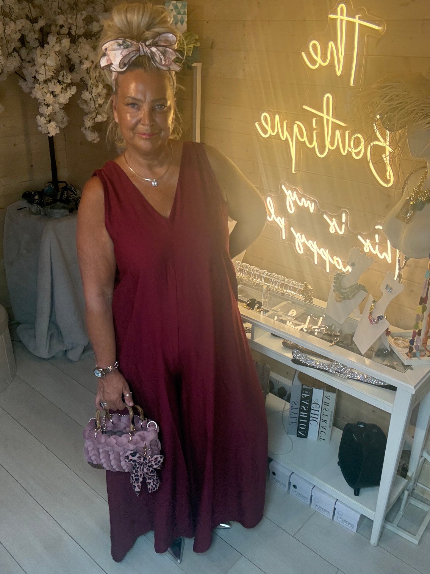 Woman wearing Merlot Burgundy Sleeveless V-Neck Jumpsuit with Lavinia Chunky Woven Tote Bag in lilac with leopard bow in The Ultimate Ladies Boutique