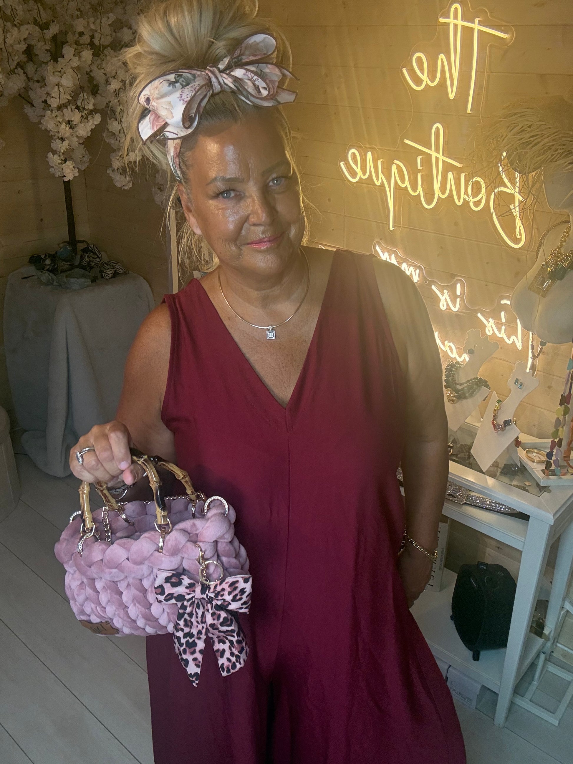 Close up of model holding Lavinia Chunky Woven Tote Bag in lilac with leopard print bow charm styled with Merlot Burgundy Jumpsuit