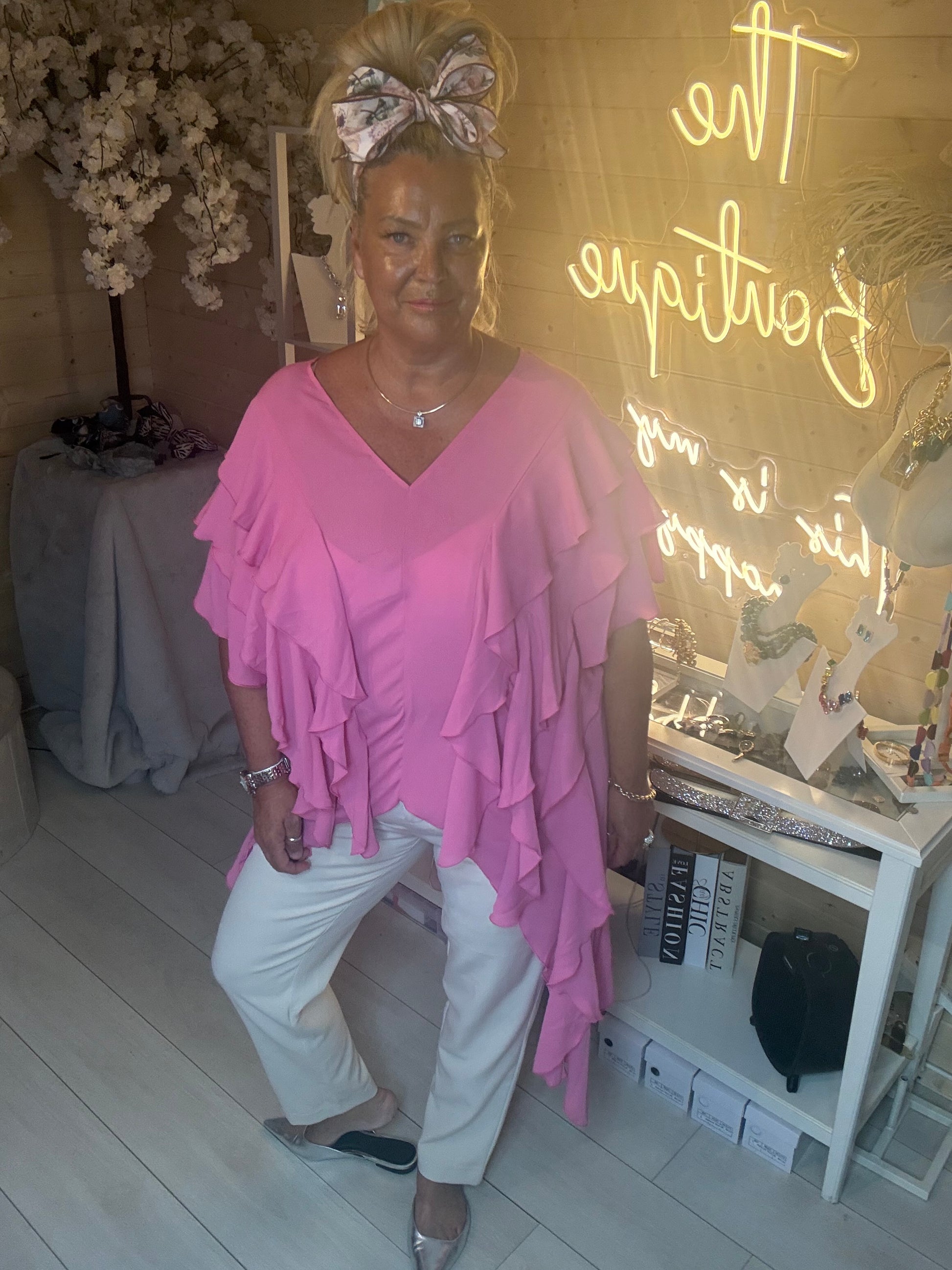 Full length view of Fiesta Hot Pink Tiered Ruffle Top with white trousers and silver flat shoes showing relaxed floaty silhouette one size 14-20