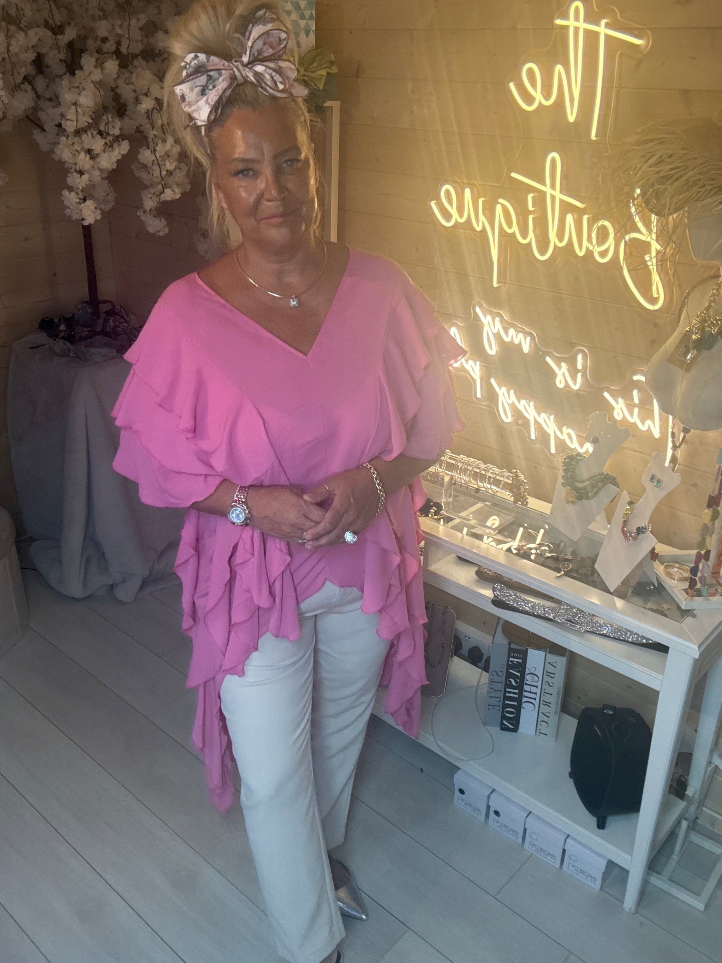 Back view of Fiesta Hot Pink Tiered Ruffle Top showing stunning open V-back detail with cascading pink ruffle layers and white trousers