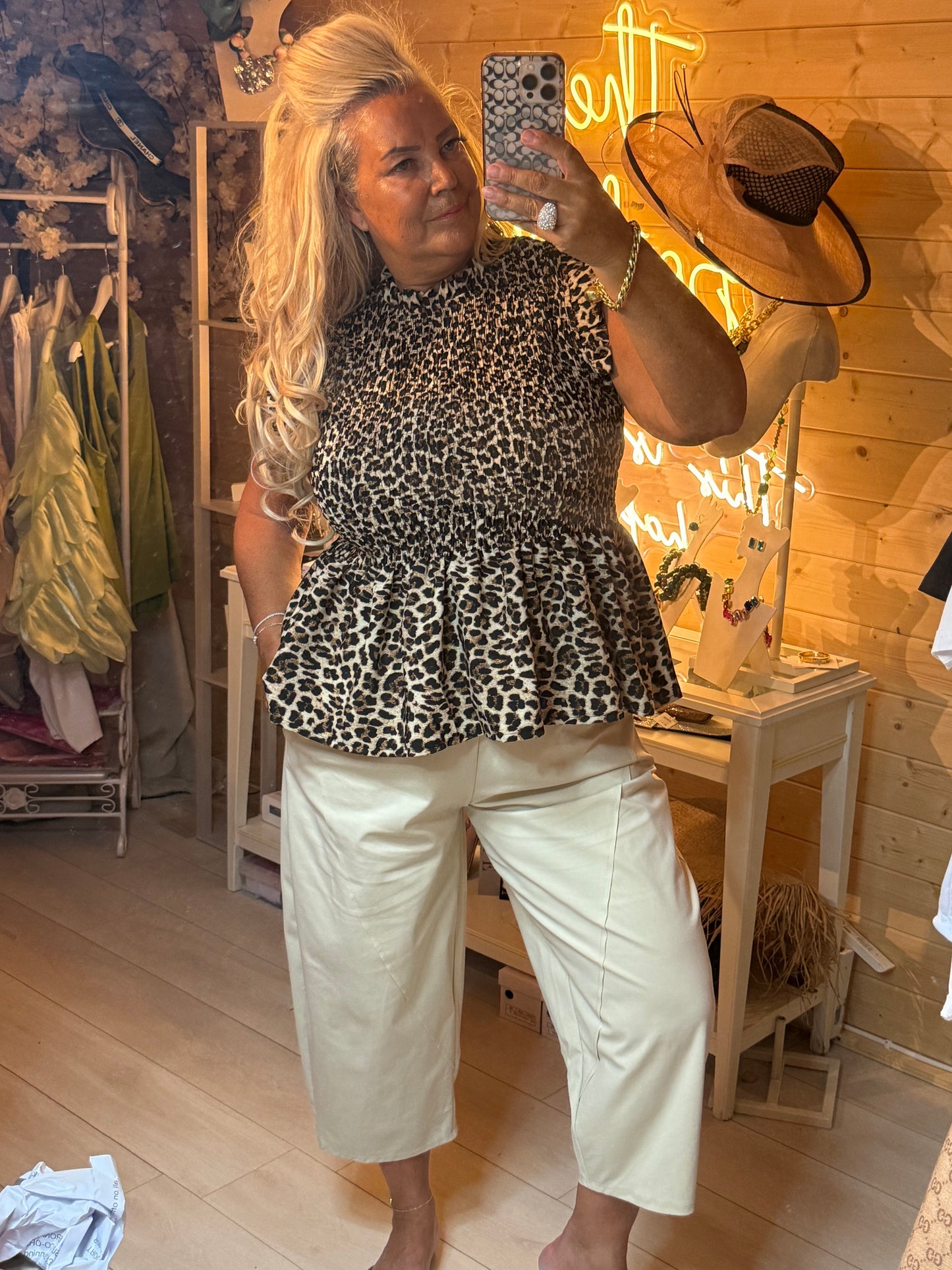 Leopard print peplum top mirror selfie – showing full outfit with stone cropped carrot trousers and boutique setting