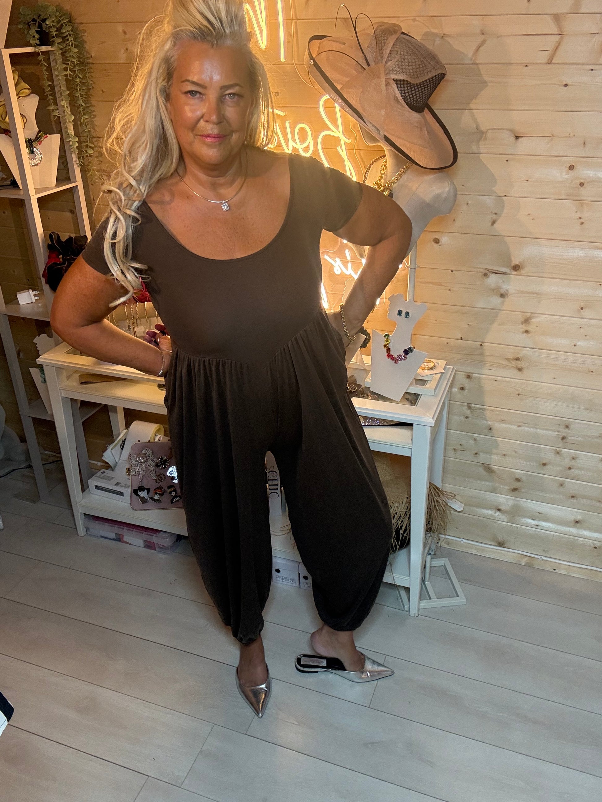 Black harem pocket jumpsuit with scoop neck – full length front view styled with silver mules, boutique setting