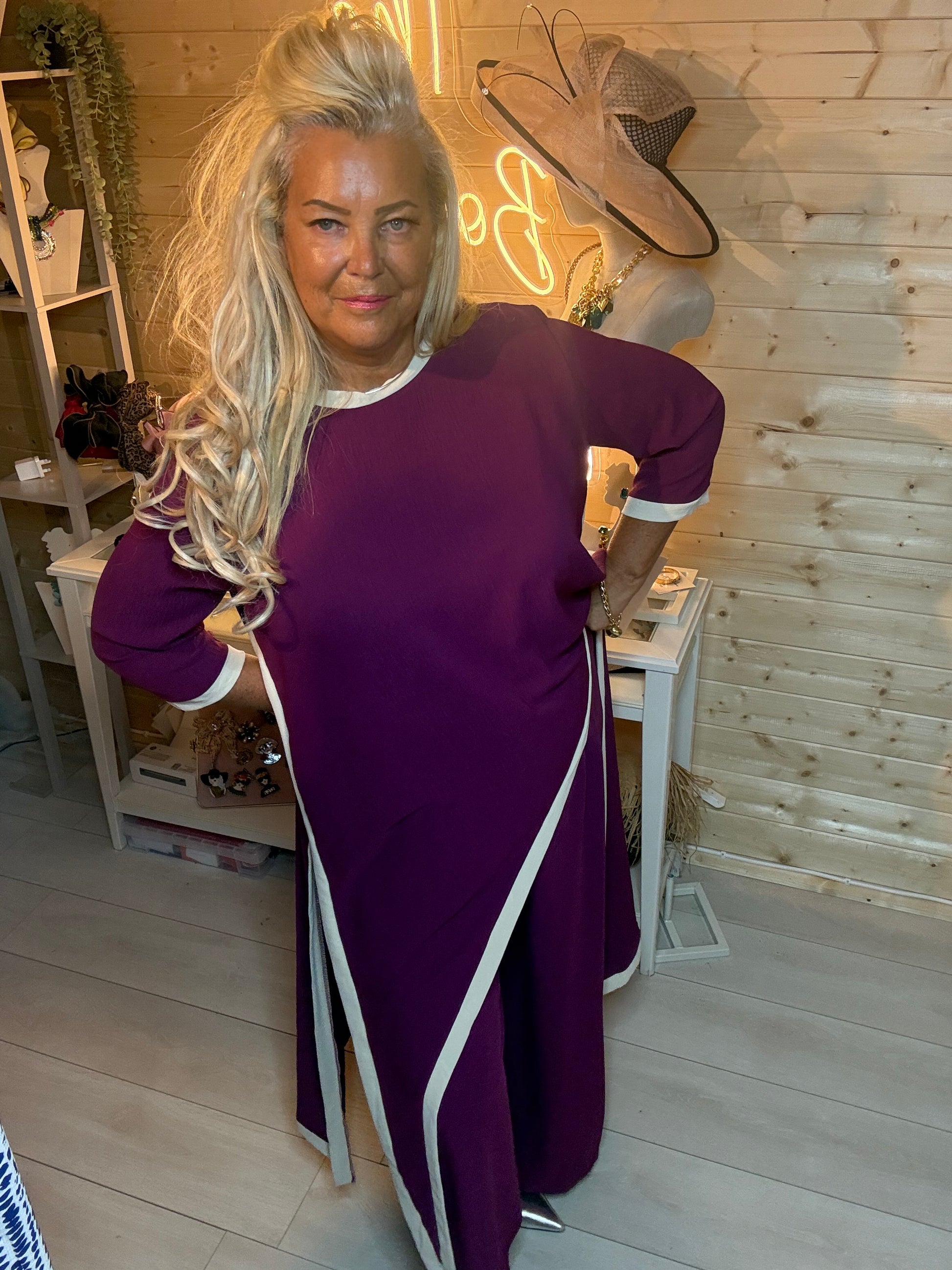 Plum asymmetric longline top worn as maxi dress – back three quarter view showing dramatic diagonal split hem and contrast trim cuffs